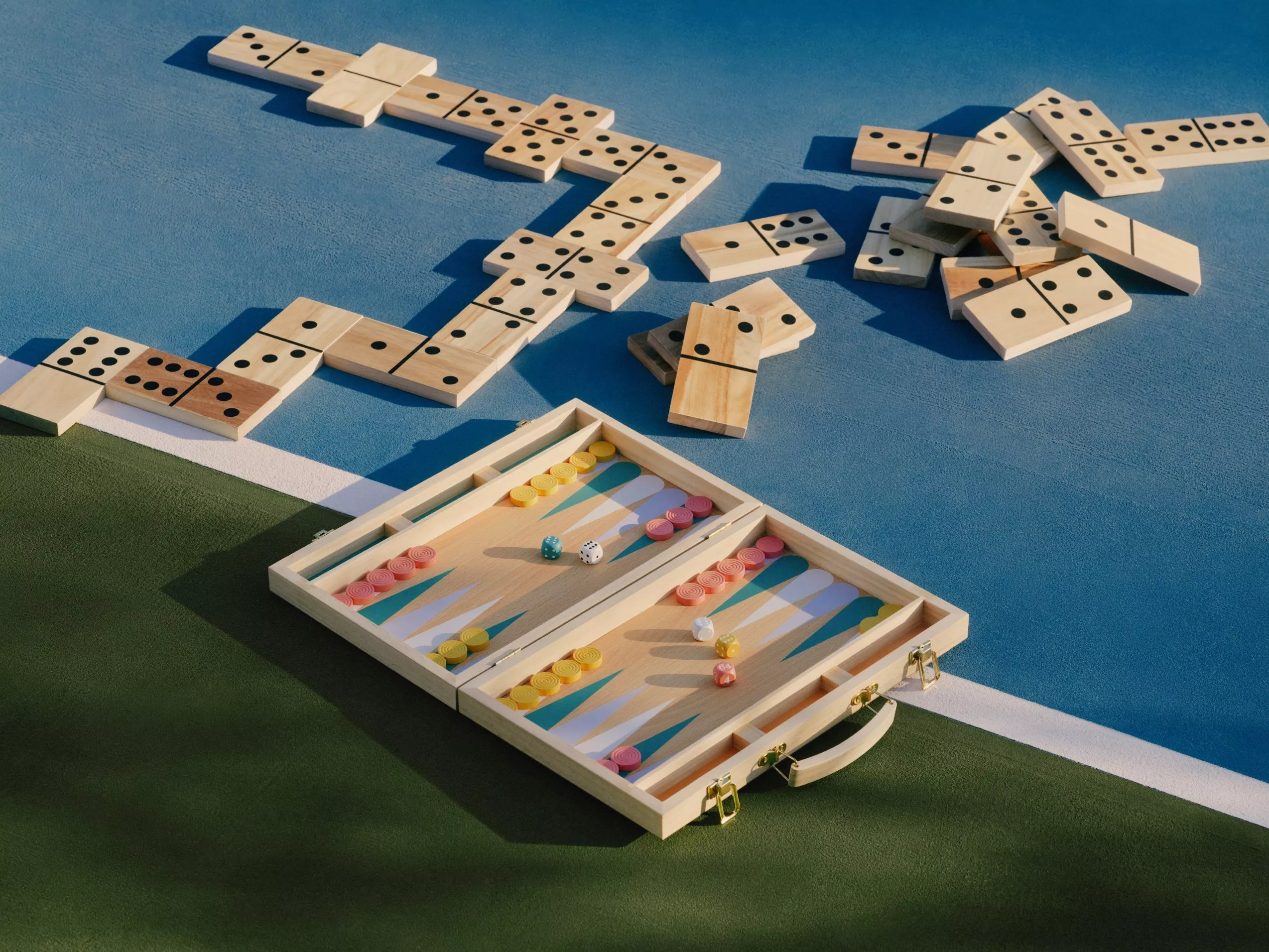 Wooden dominoes and travel backgammon set with colourful counters and dice on an outdoor court surface