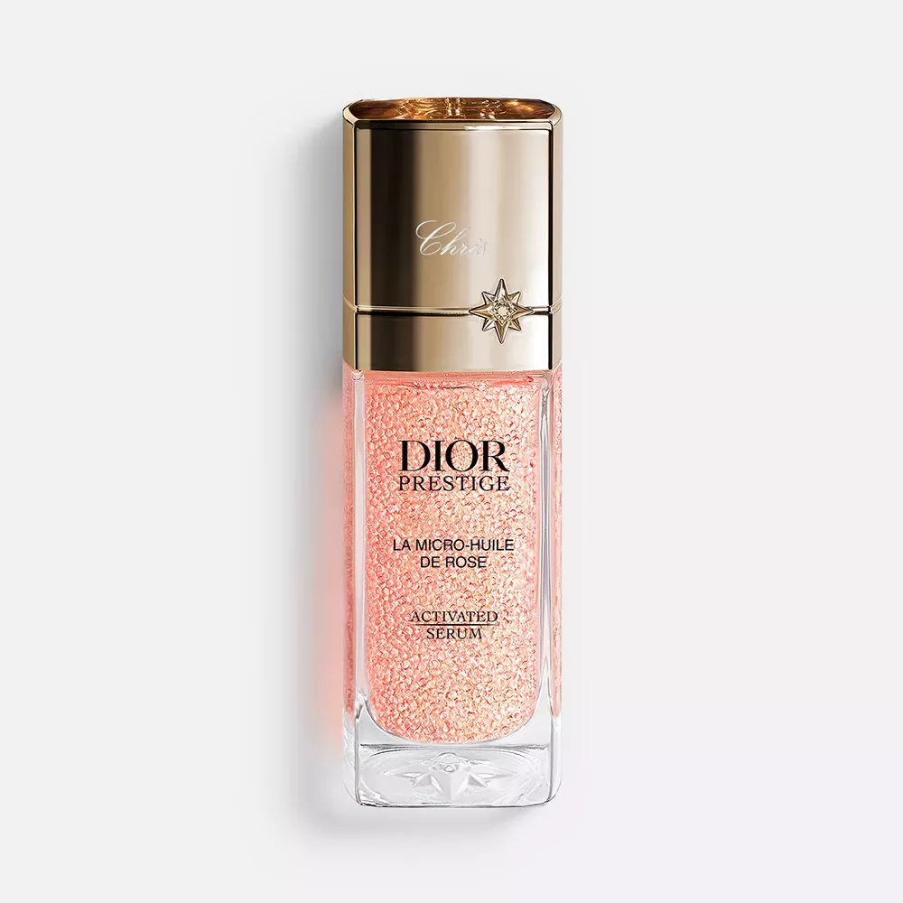 Luxurious Dior Prestige serum in an elegant glass bottle with sparkling pink micro-particles and a gold cap.