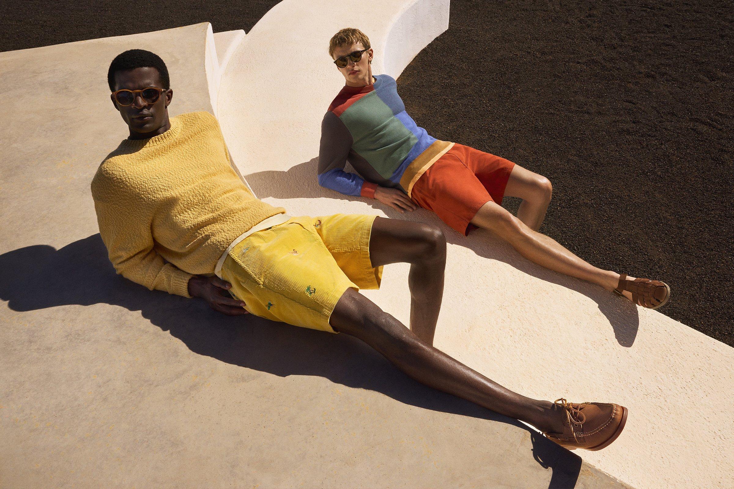 Two male models wearing colourful yellow, green and orange outfits