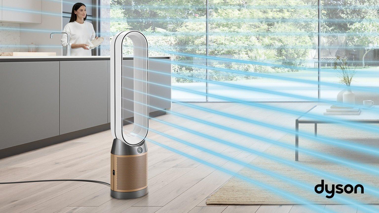 Dyson purifiers in the middle of the hall next to grey sofa and small wooden table with big window in the background