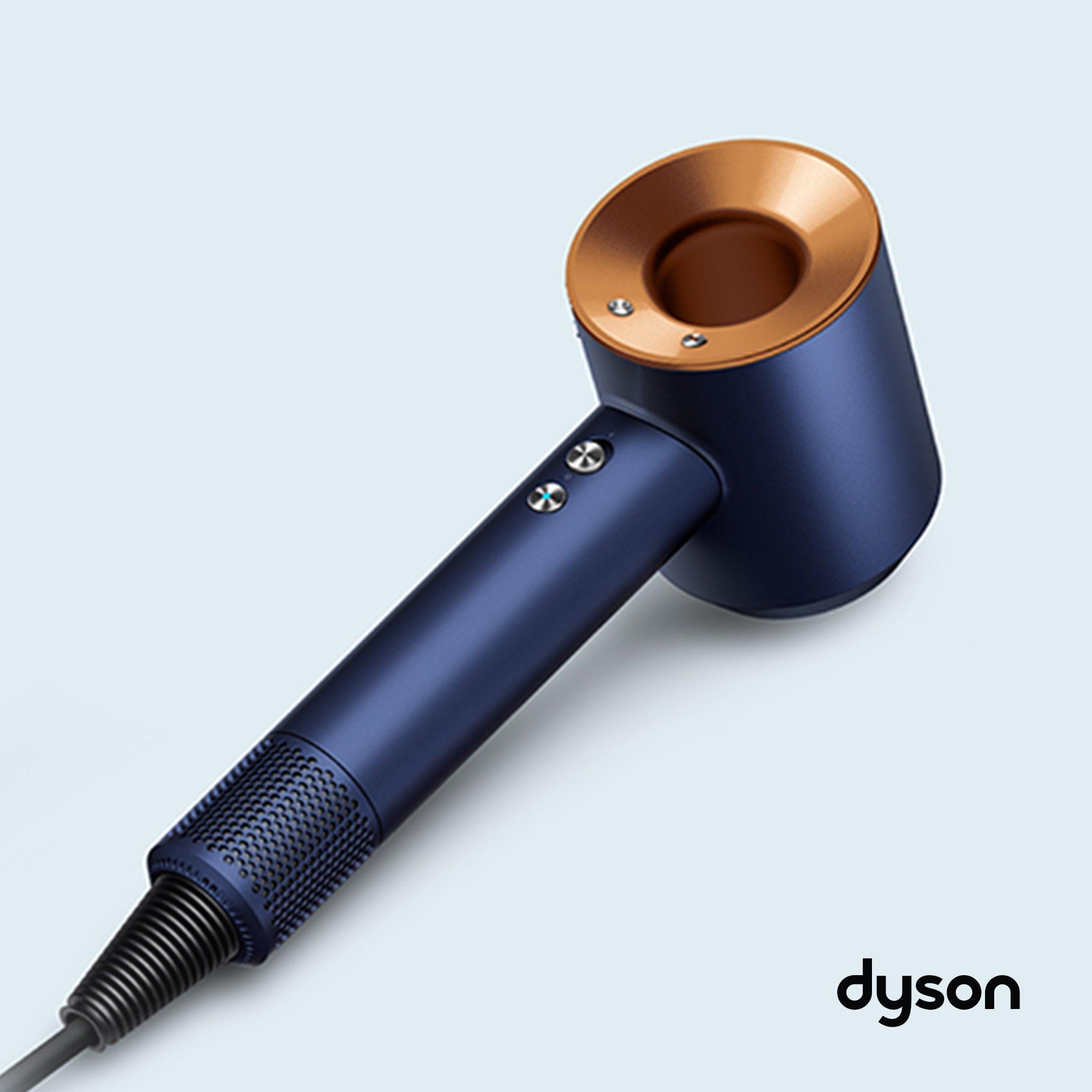 A Dyson Supersonic hair dryer in a sleek navy blue and copper finish on a light background.