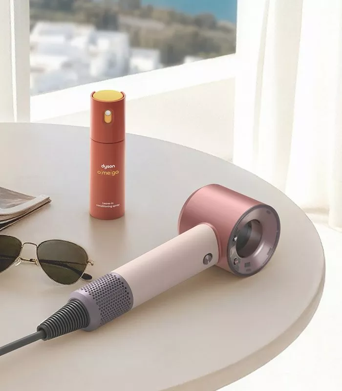 Dyson Supersonic hair dryer and Dyson Chitosan Omega styling serum on a table by a sunny window