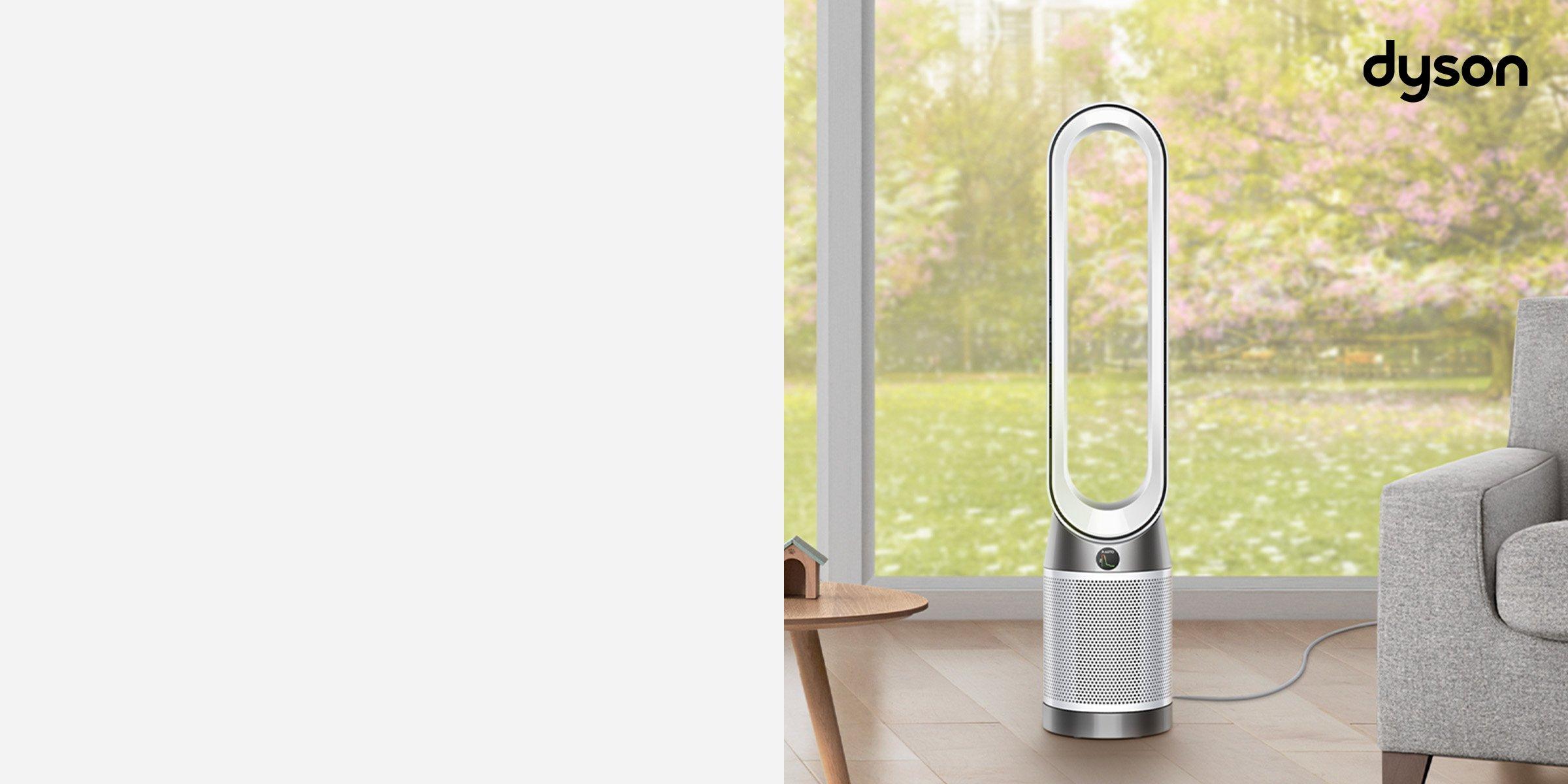 Dyson purifiers in the middle of the hall next to grey sofa and small wooden table with big window in the background