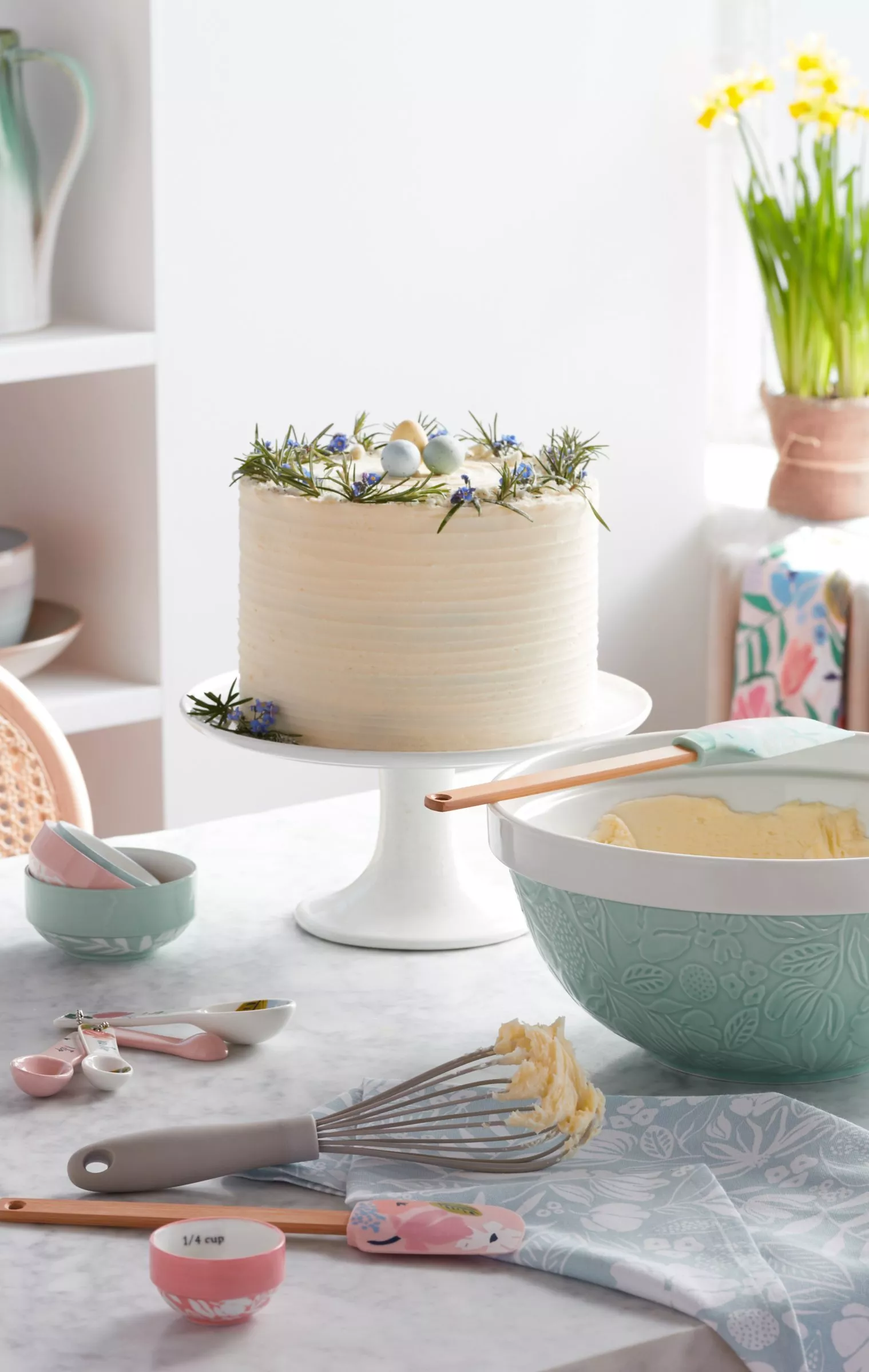 Wooden kitchen utensils on a round board, with flour, sugar jars, and milk in a measuring jug nearby.