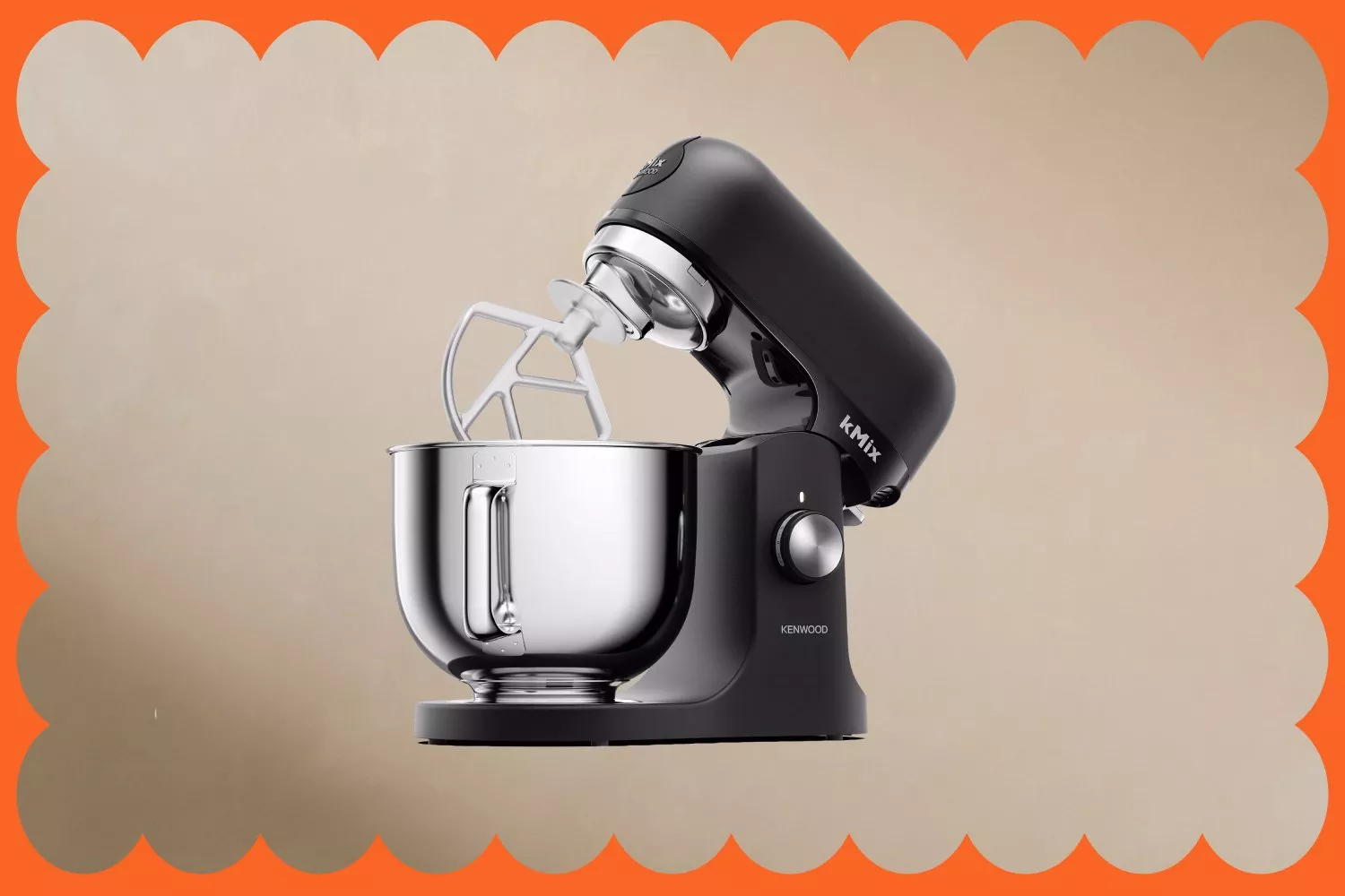A sleek black Kenwood kMix stand mixer with a stainless steel mixing bowl, set against a beige background.