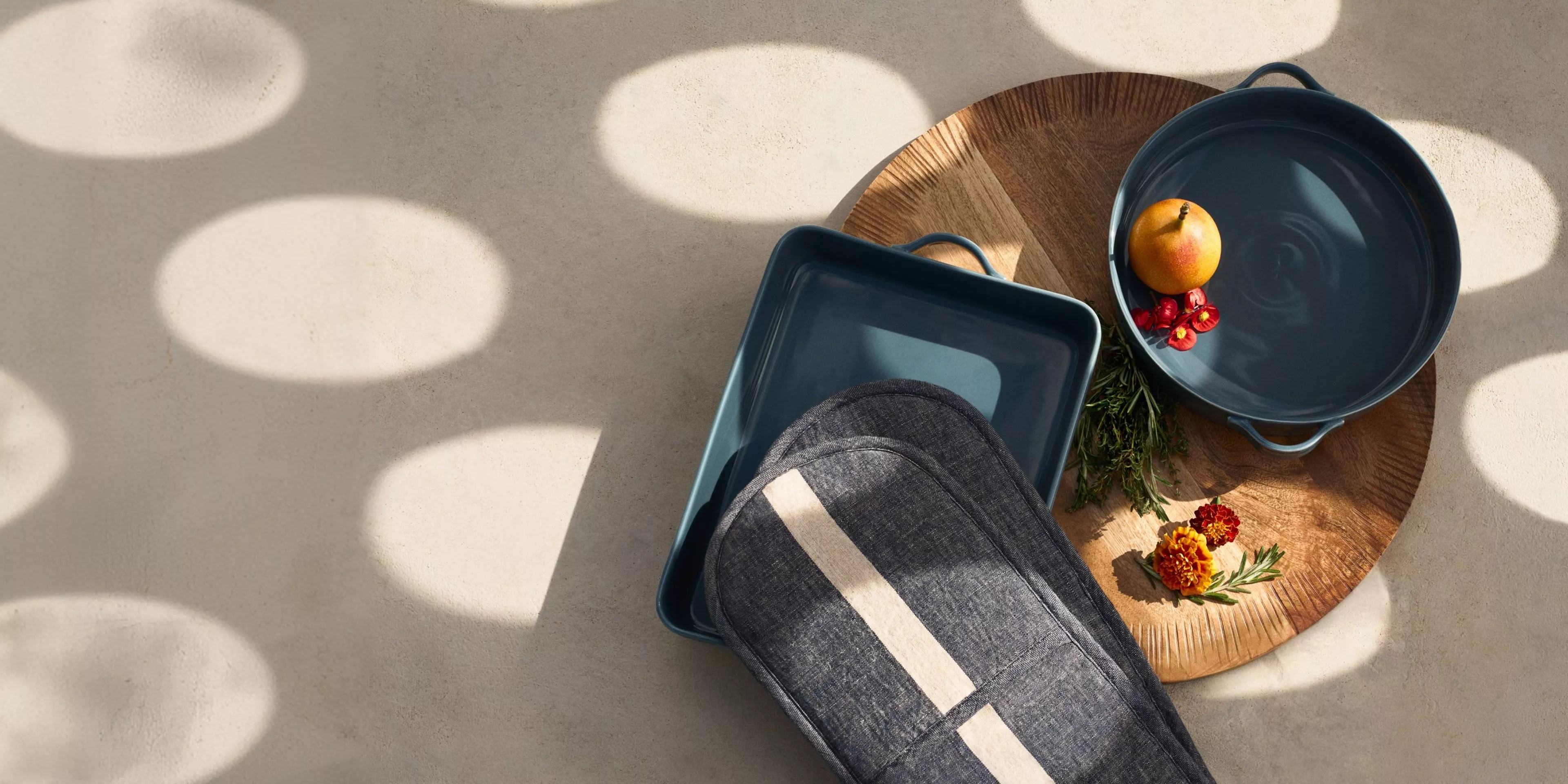 a blue cooking pan and oven glove on a wooden chopping board 