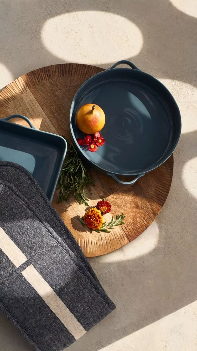 a blue cooking pan and oven glove on a wooden chopping board 