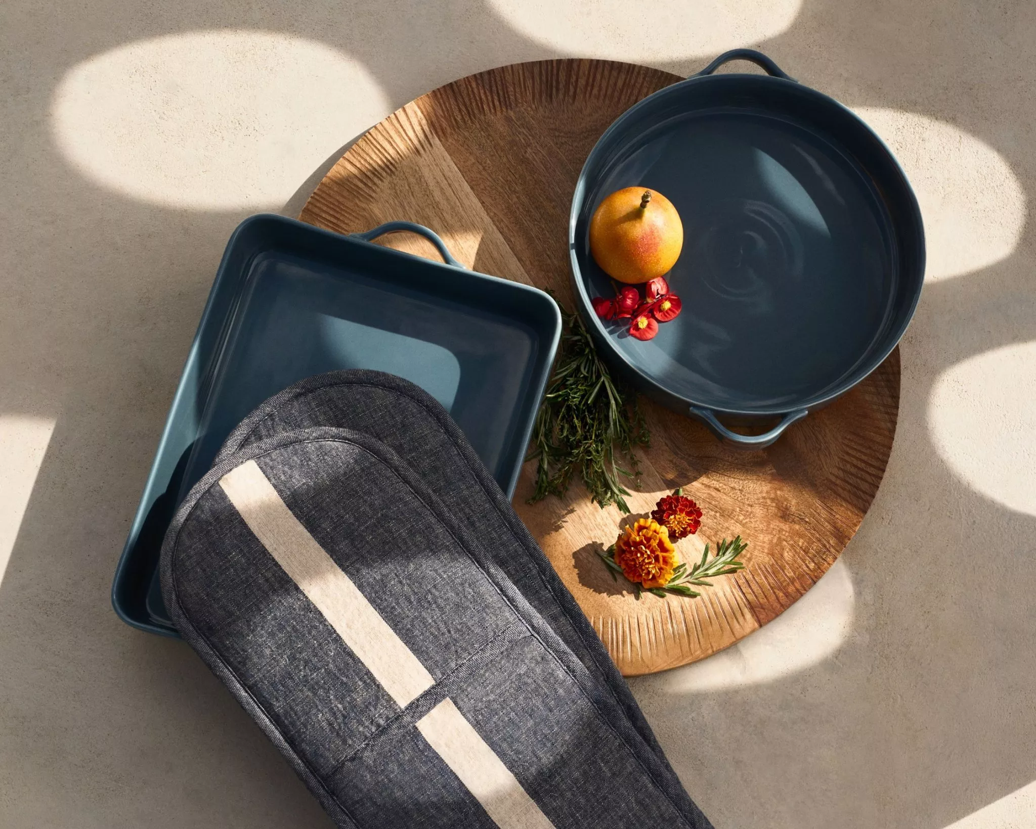 a blue cooking pot and oven glove on a wooden chopping board