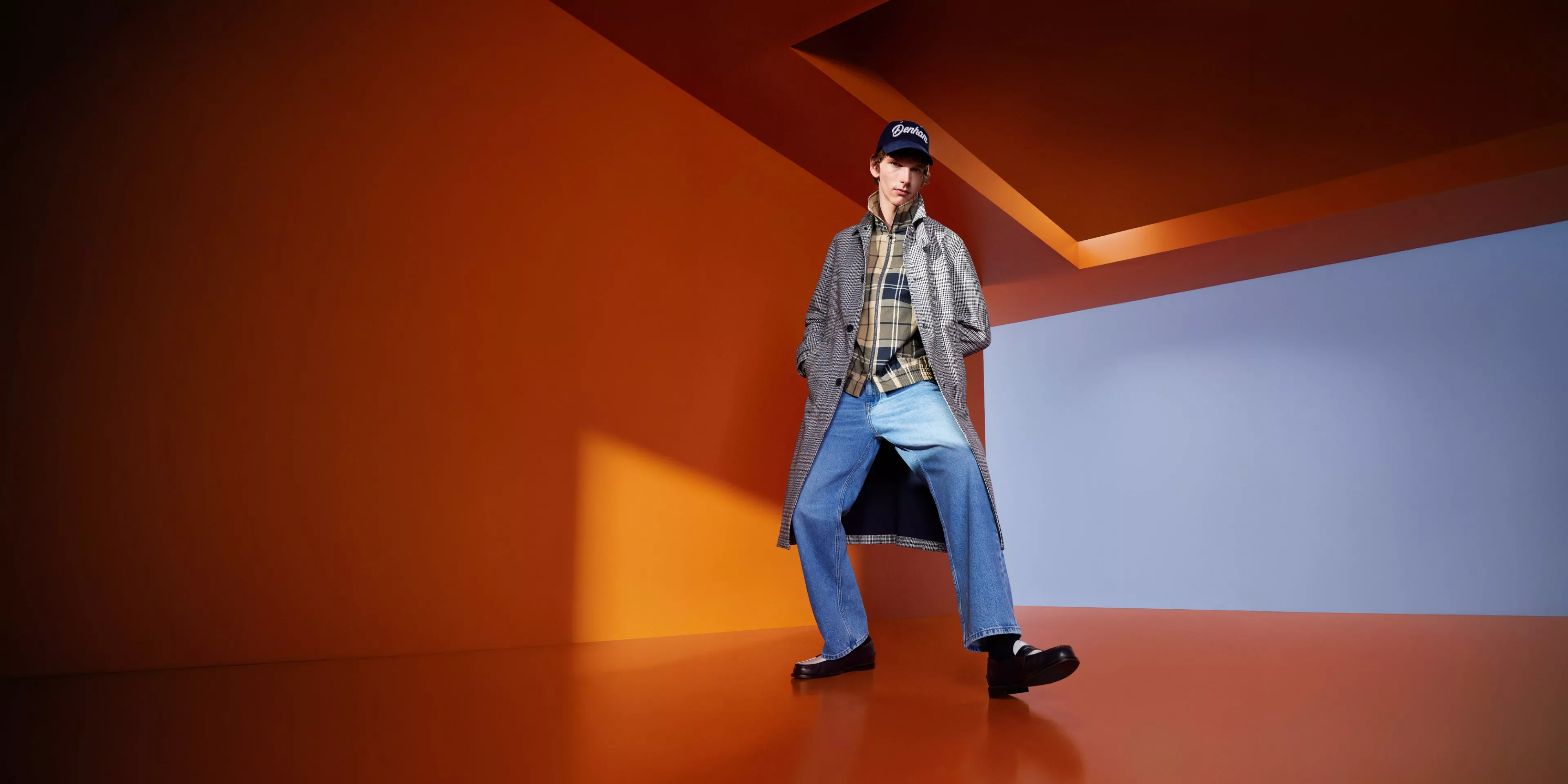 two men, one in off white denim and the other in dark blue denim on a concrete building with blue skies behind 