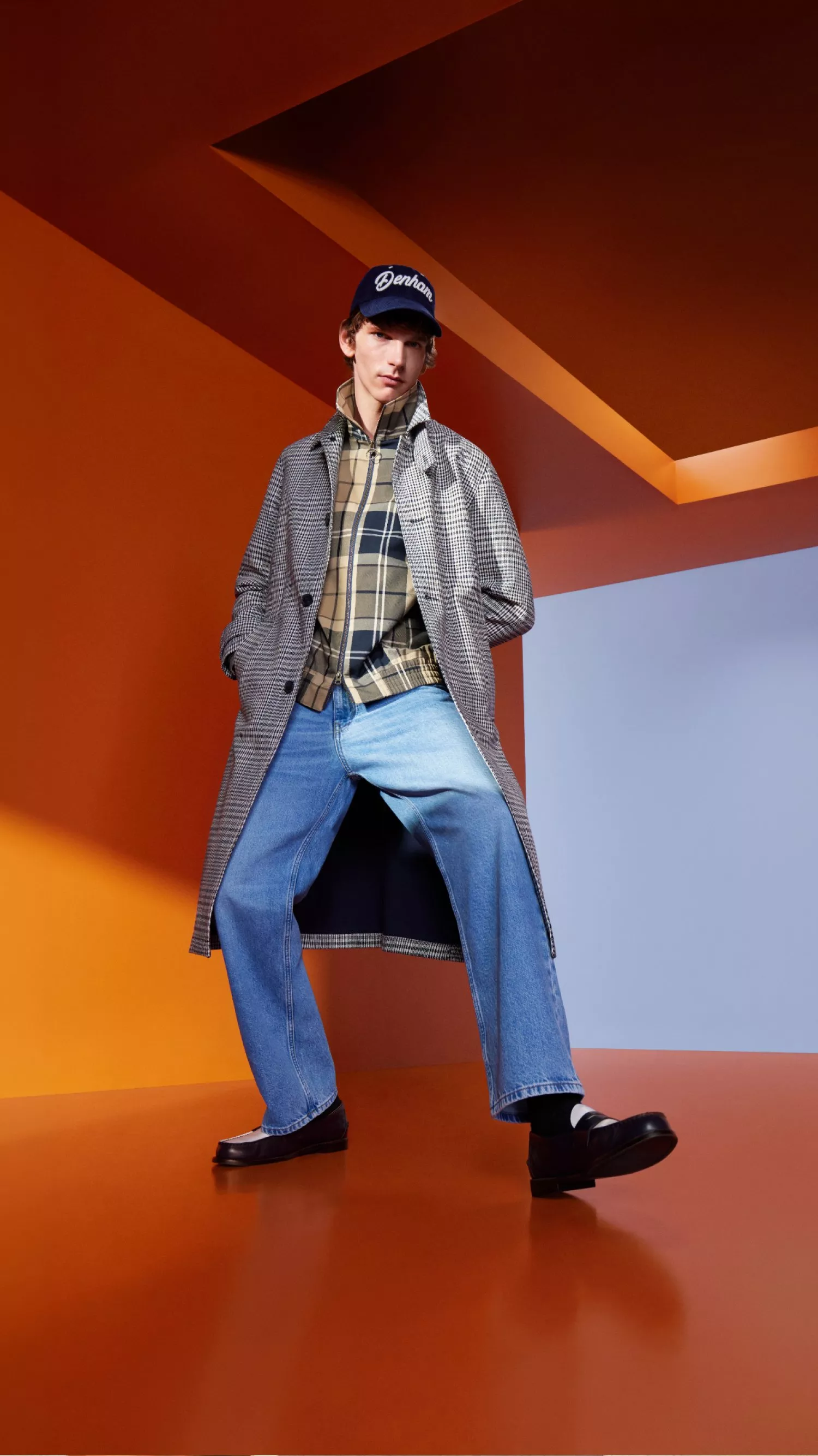 two men, one in off white denim and the other in dark blue denim on a concrete building with blue skies behind 