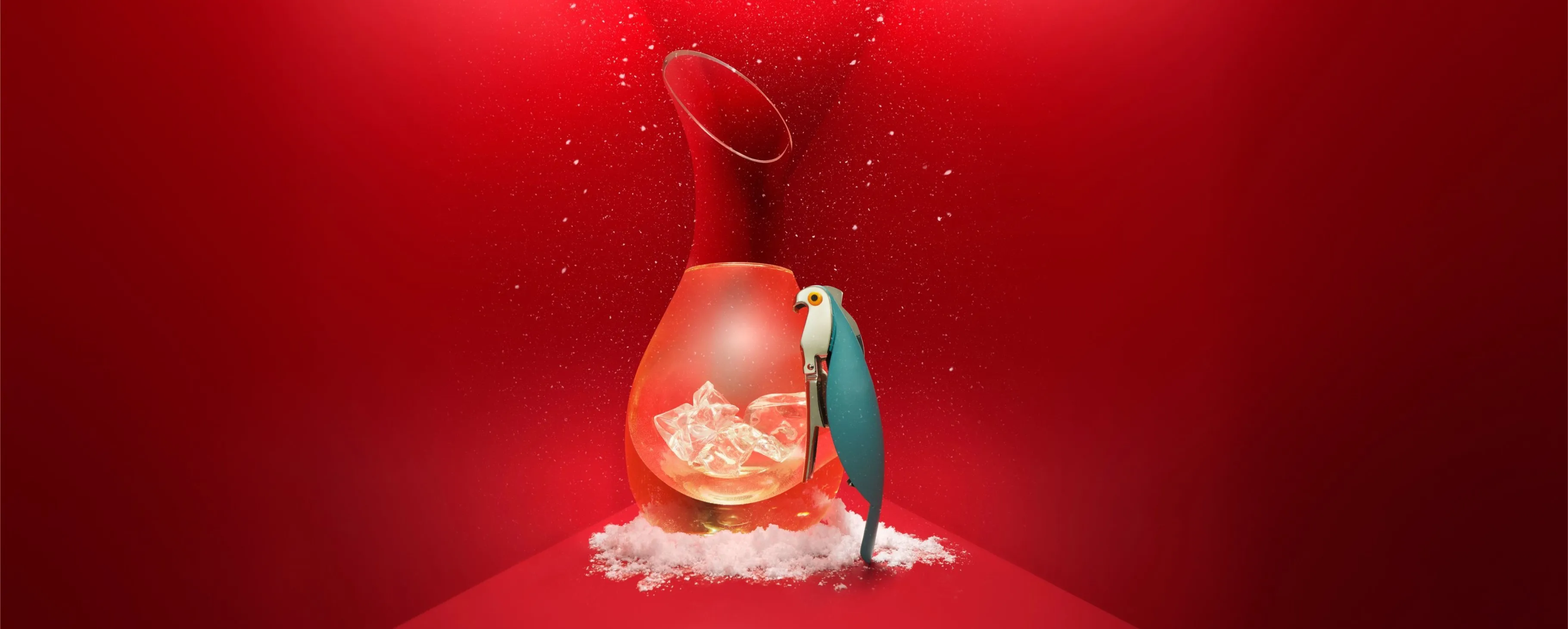 Blue parrot figurine beside a glass jug with ice cubes and faux snow on a bold red background