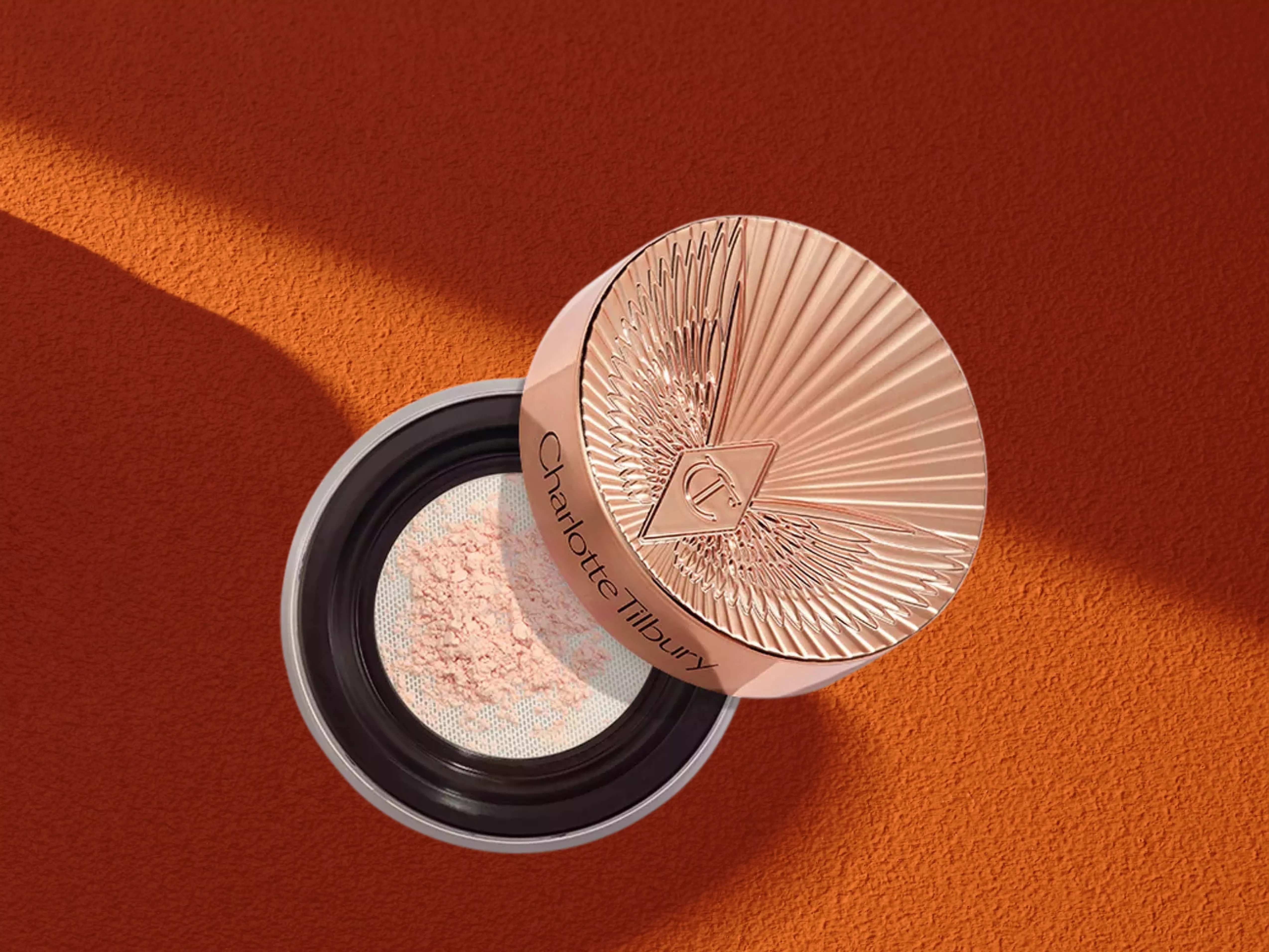 Charlotte Tilbury Airbrush Flawless Blur Loose Powder on a orange background