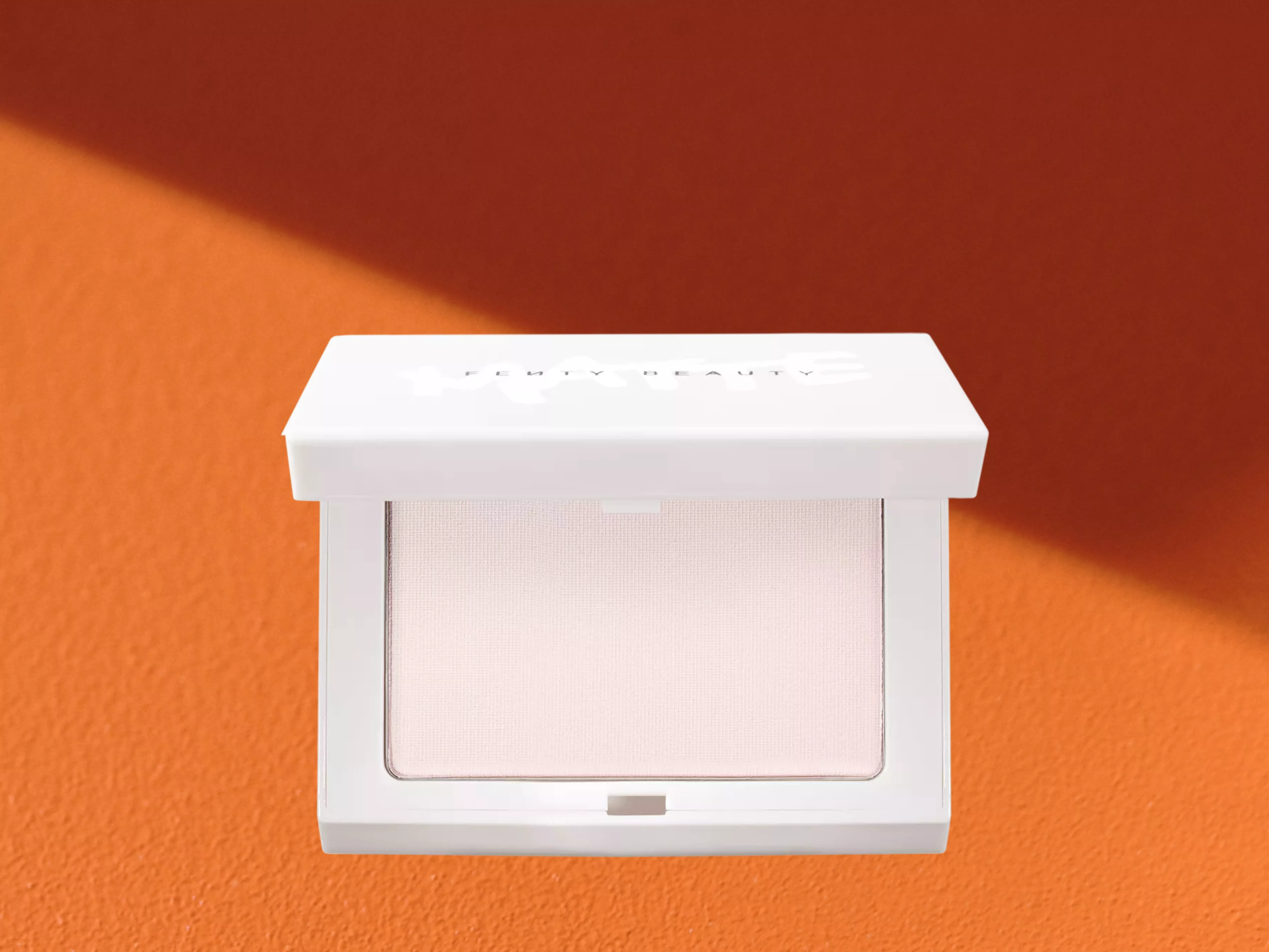 Fenty Beauty Invisimatte Instant Setting Blotting Powder on a orange background 