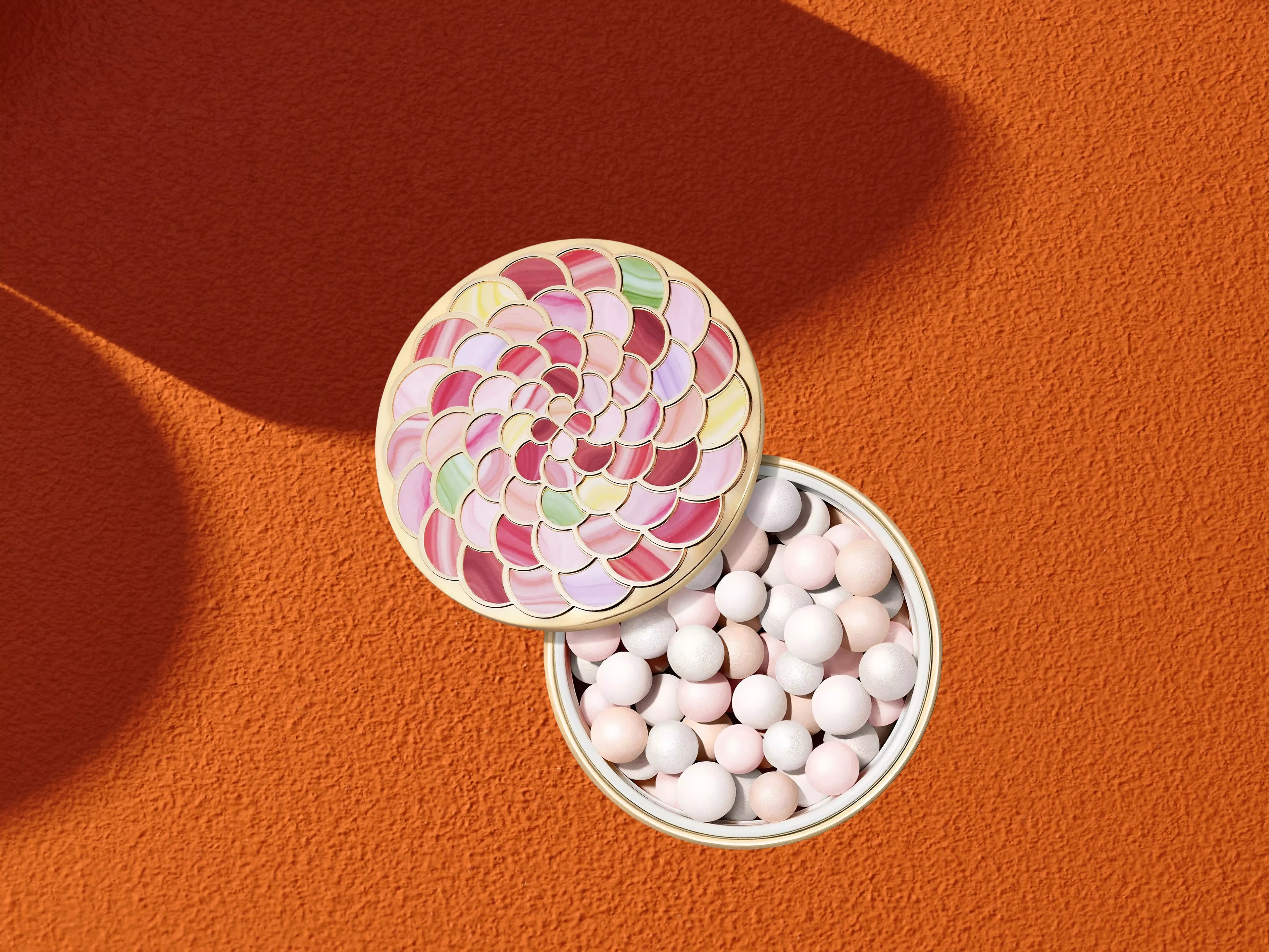 Guerlain Météorites Light-Revealing Pearls Of Powder on a orange background