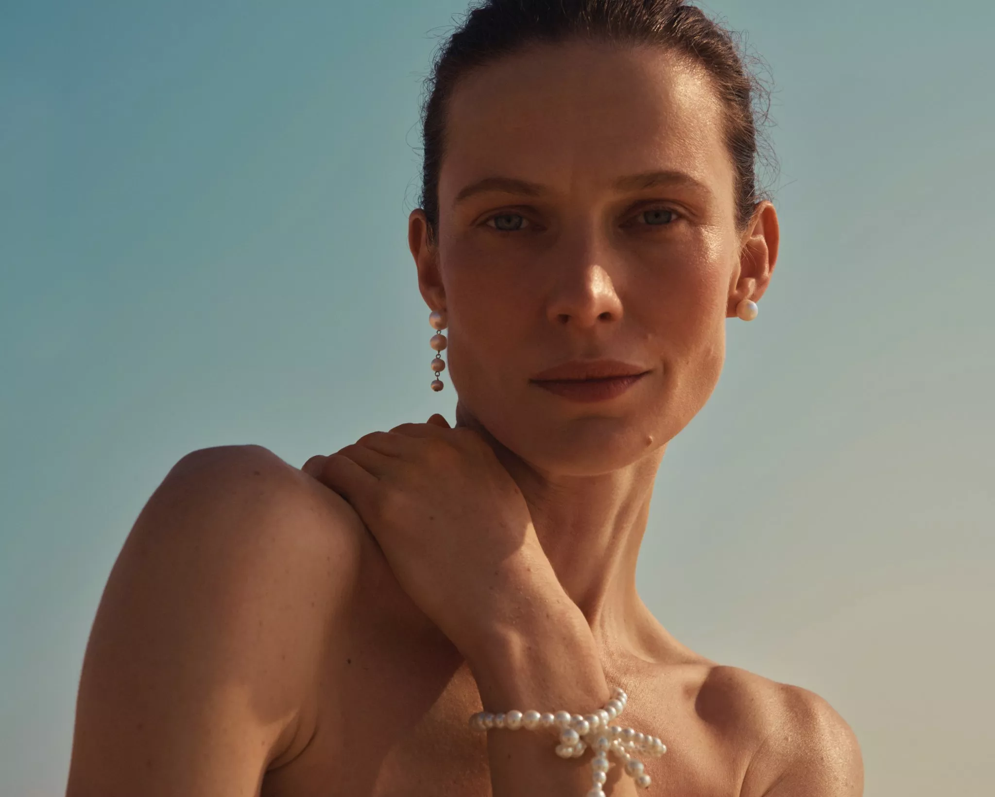 women holding her hand up to her shoulder in sunshine 