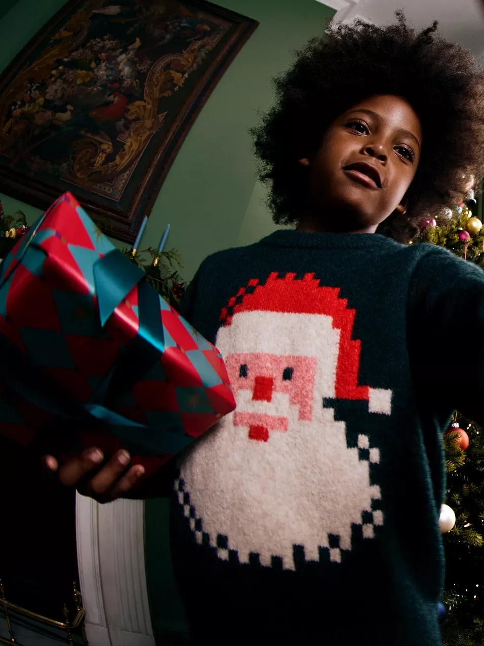 Boy in Christmas jumper holding gift