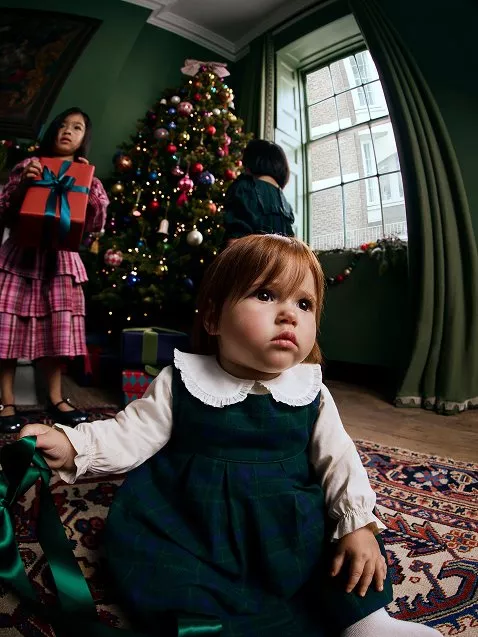 Toddler in green tartan patterned dress and white collared shirt