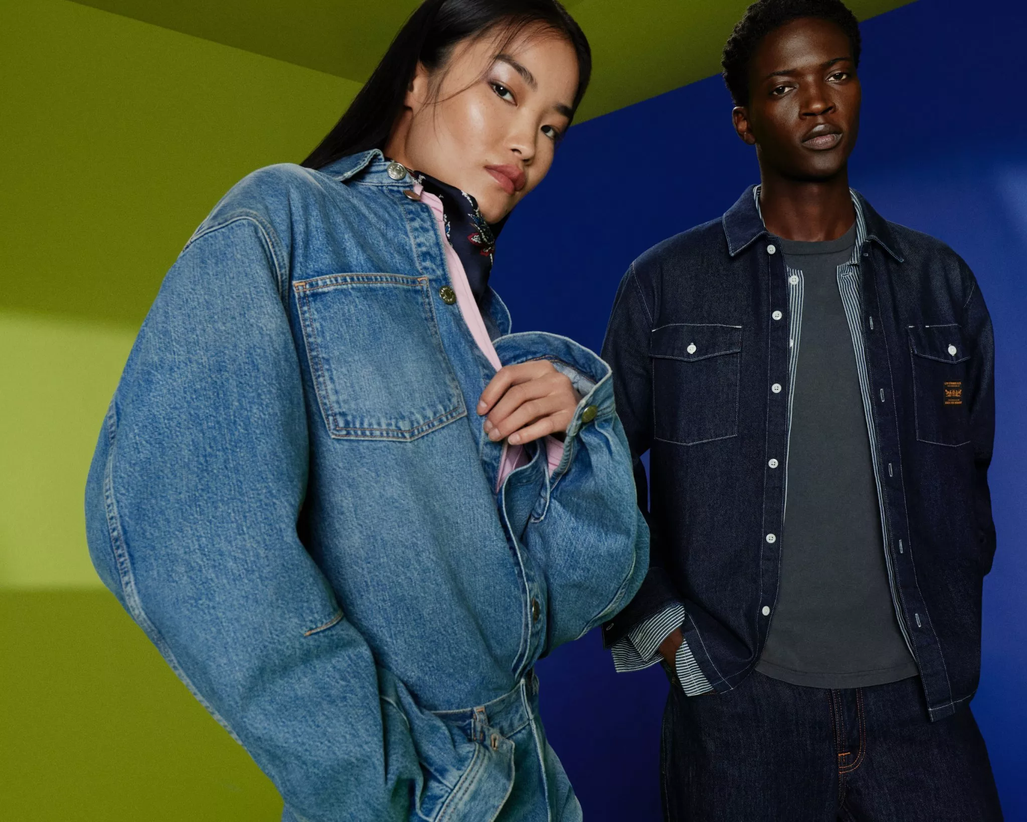 Two fashion models in denim jackets posing in a studio, showcasing modern casual streetwear style on colour block set