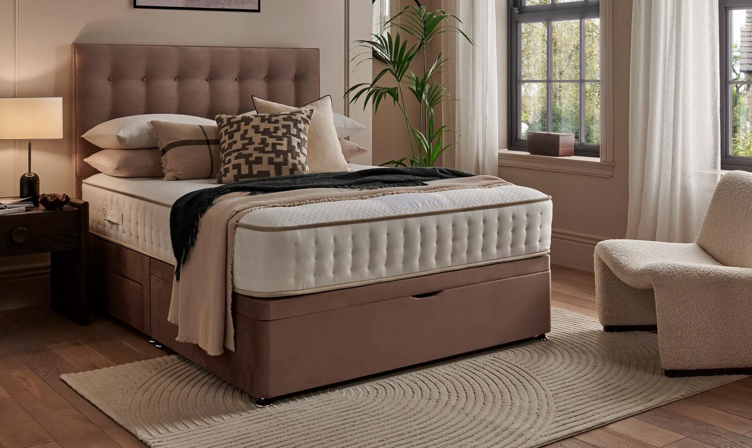 lifestyle shot of a matress on a bed with cusions on it set in modern neautral coloured room