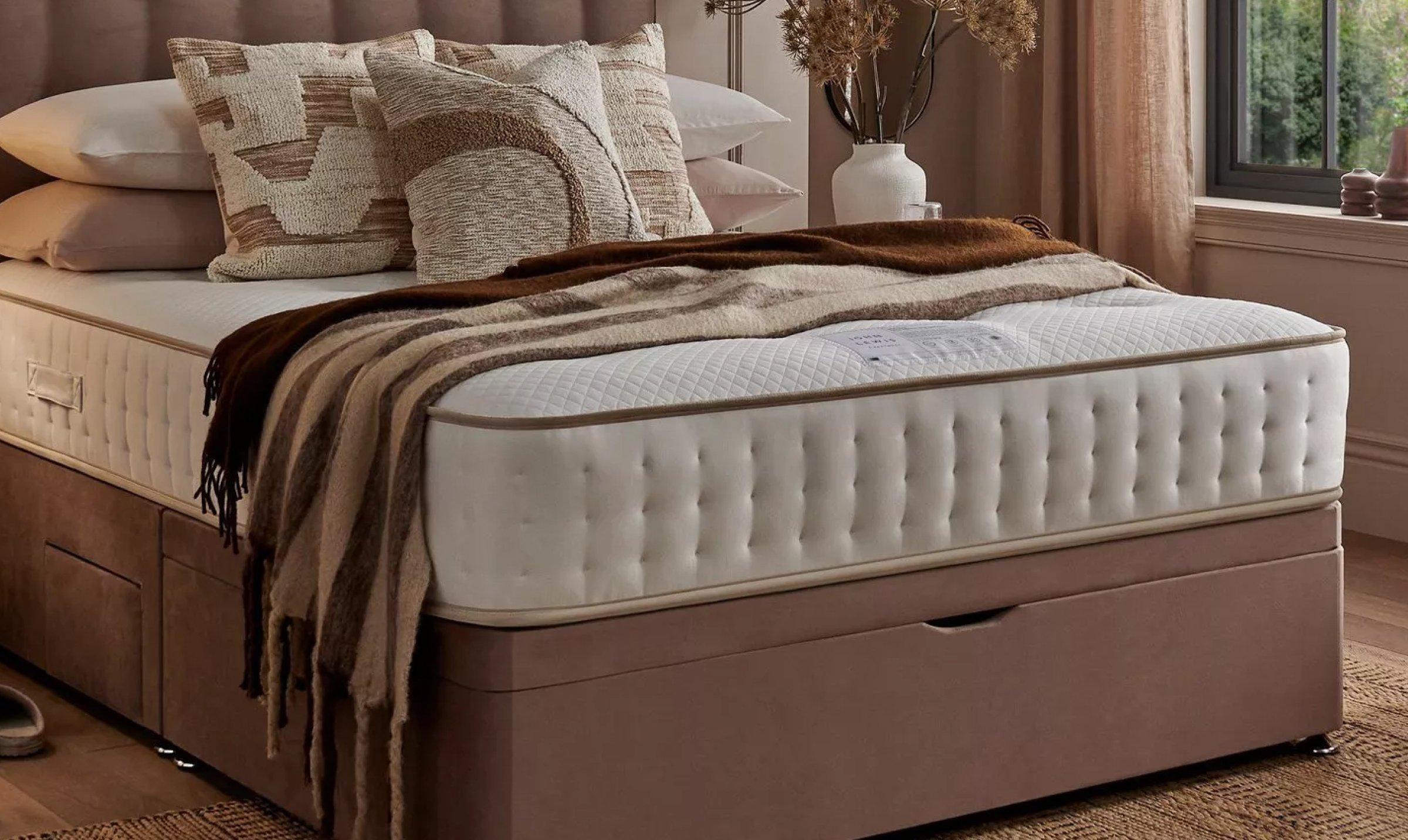 lifestyle shot of a matress on a bed with cusions on it set in modern neautral coloured room