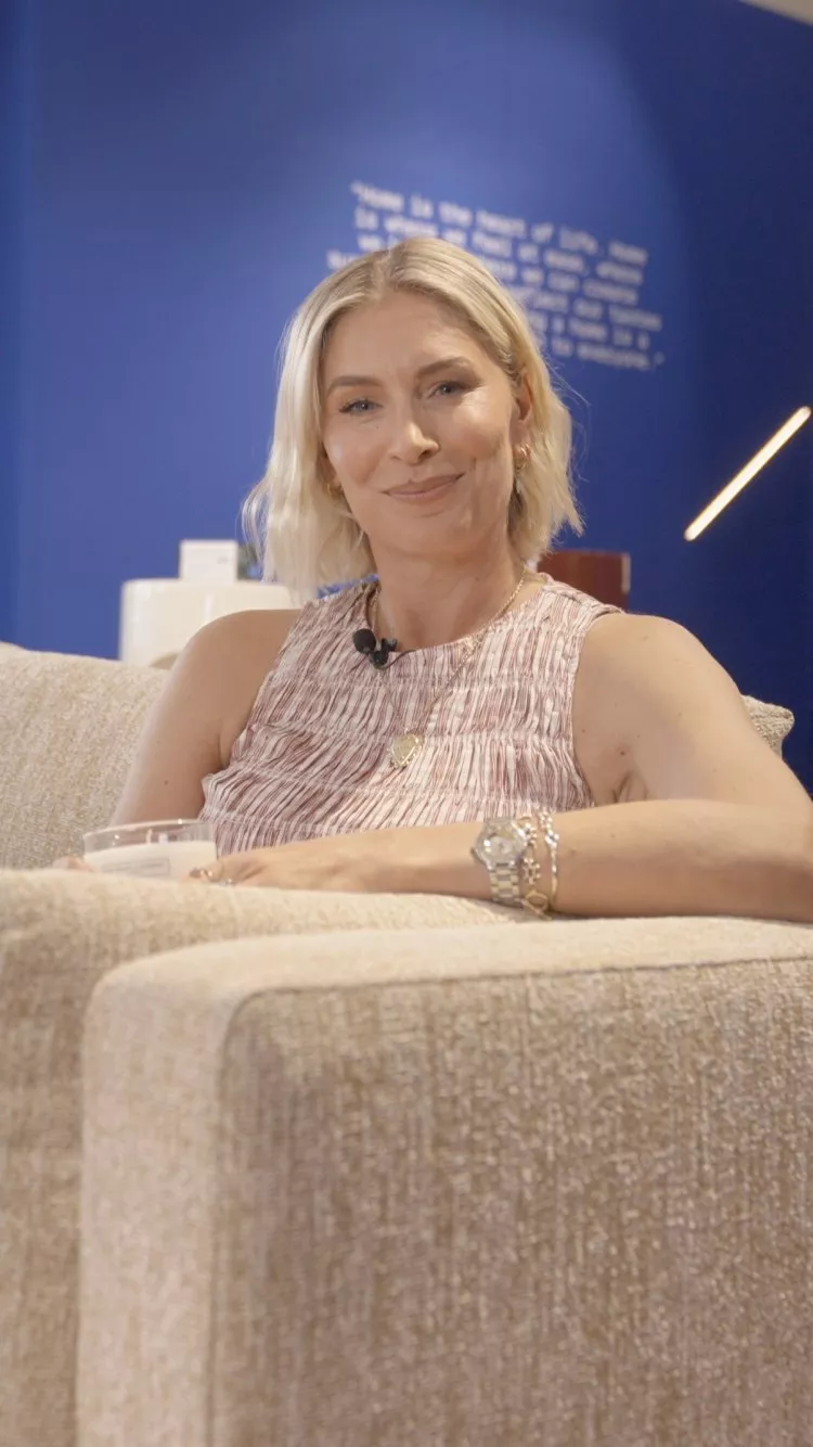 Louise Boyce seated on a sofa in a modern showroom, showcasing stylish interior design and lighting display.