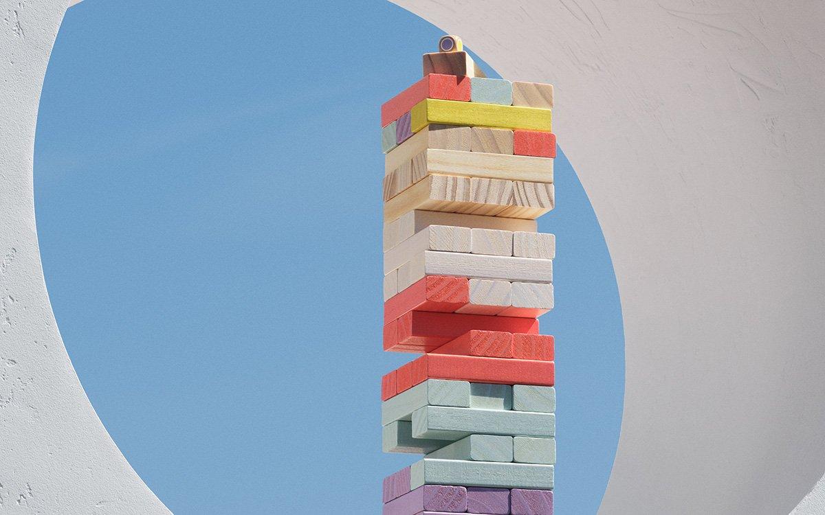 Coulourful wooden tumble block tower game sitting in a circular ledge.