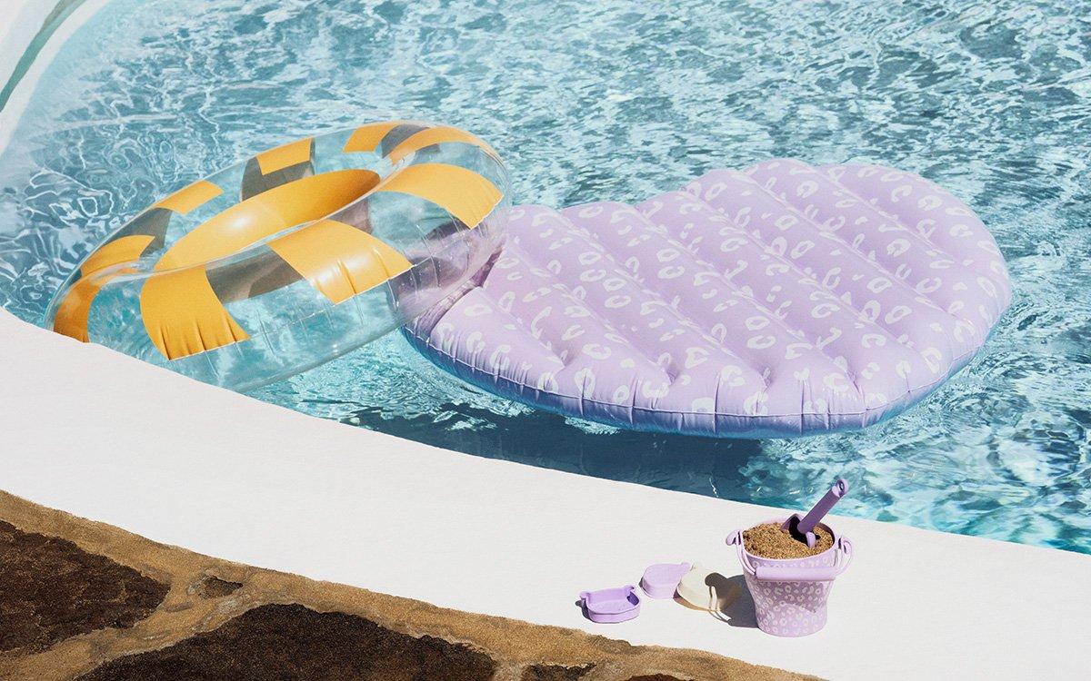 Swimming floats in a swimming pool with bucket a spade on pool side.