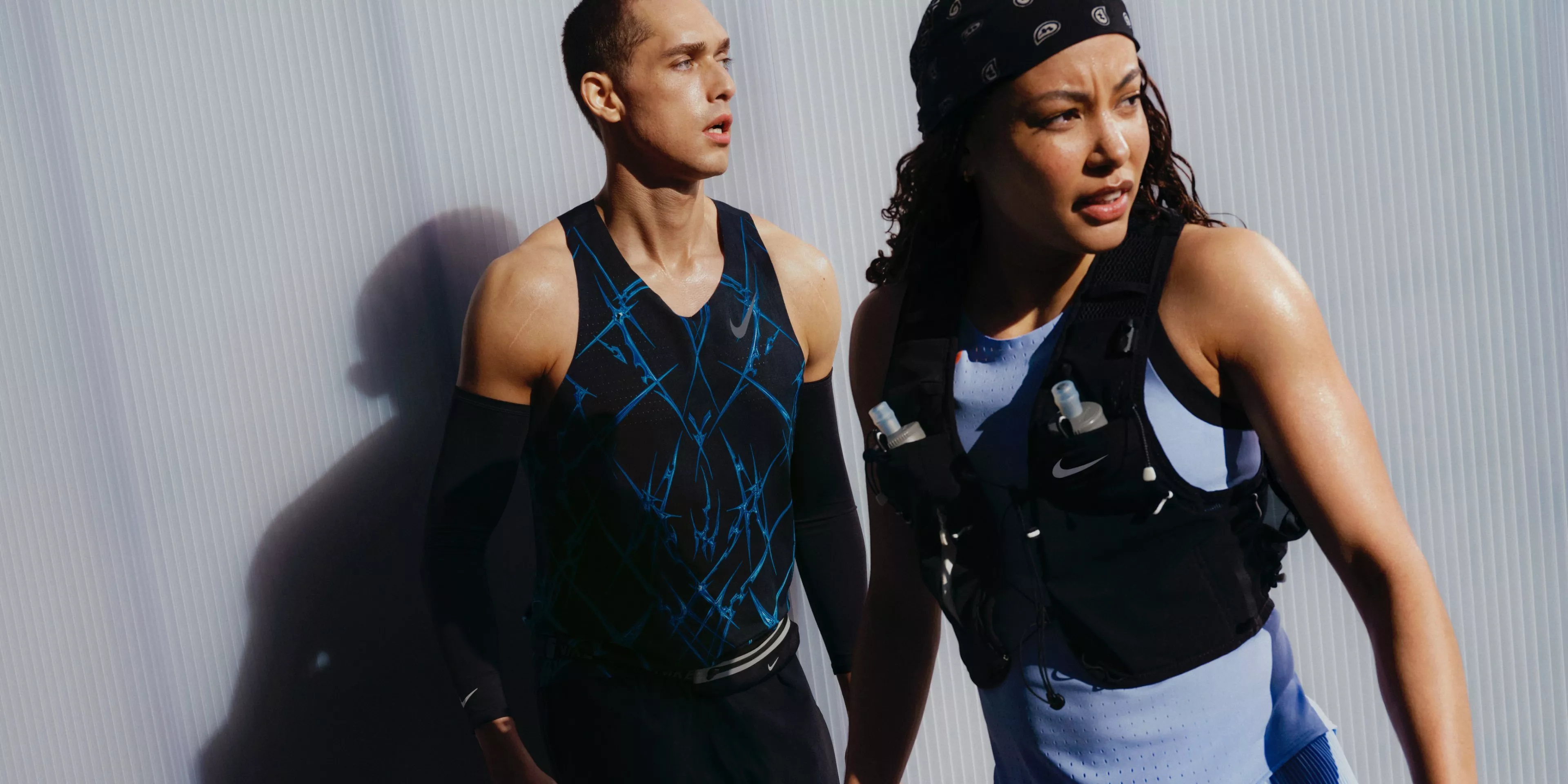 man and women wearing nike gear infron of a metal wall