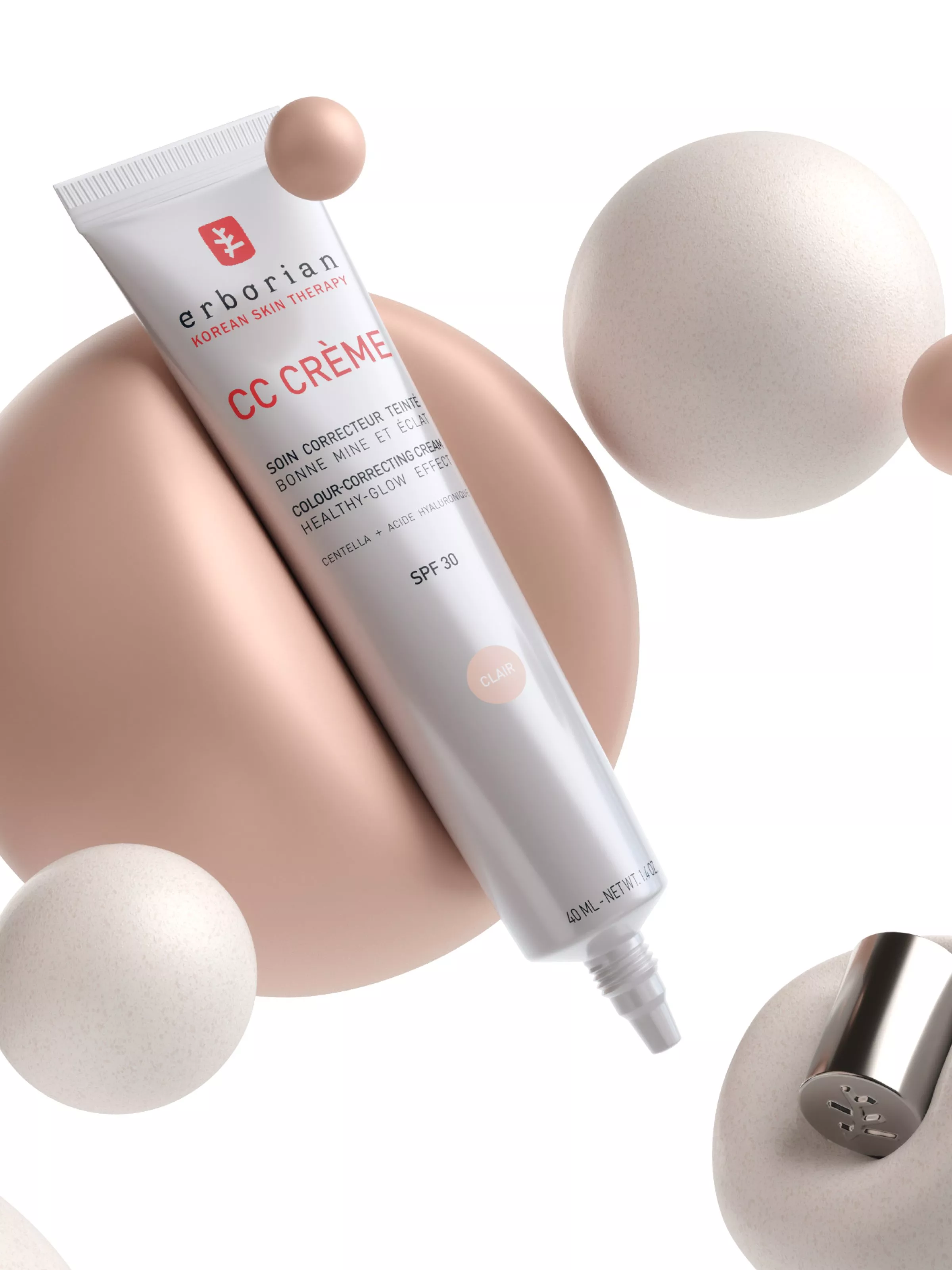 Erborian CC Crème SPF 30 colour-correcting moisturiser tube, floating with beige spheres on white background