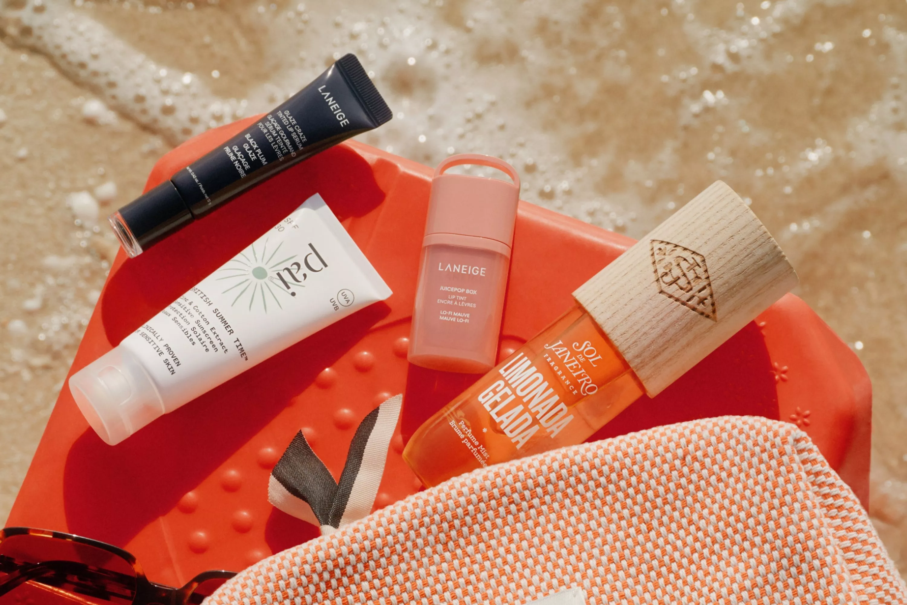 beauty product laid out on a bag on a beach 