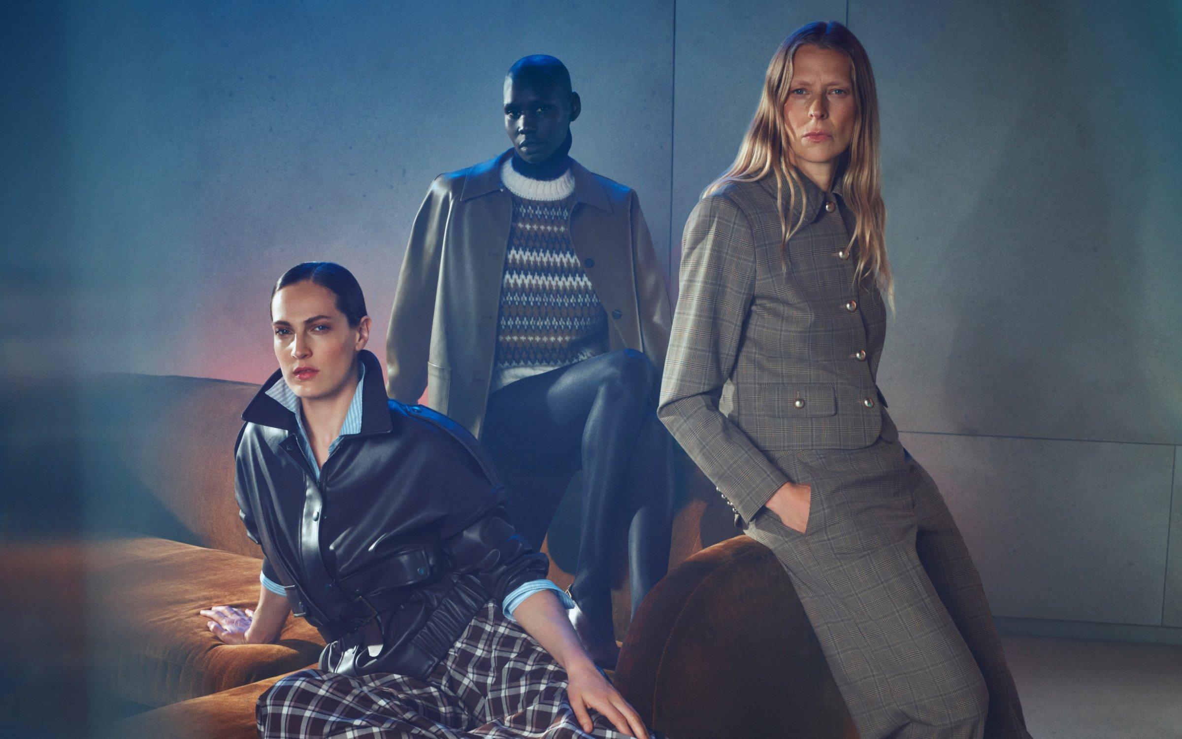 3 women dressed in fasionable coats sitting on a sofa