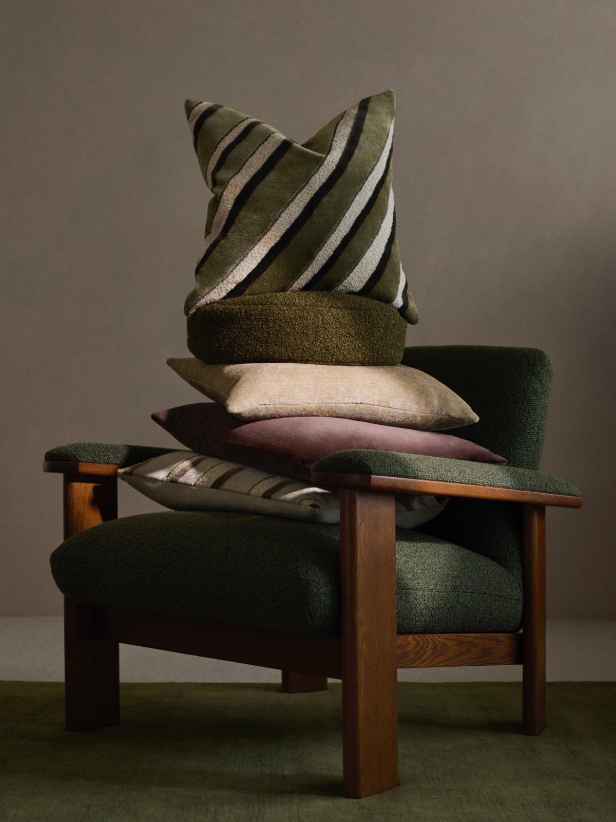 A variety of Modern Luxe cushions stacked on an armchair