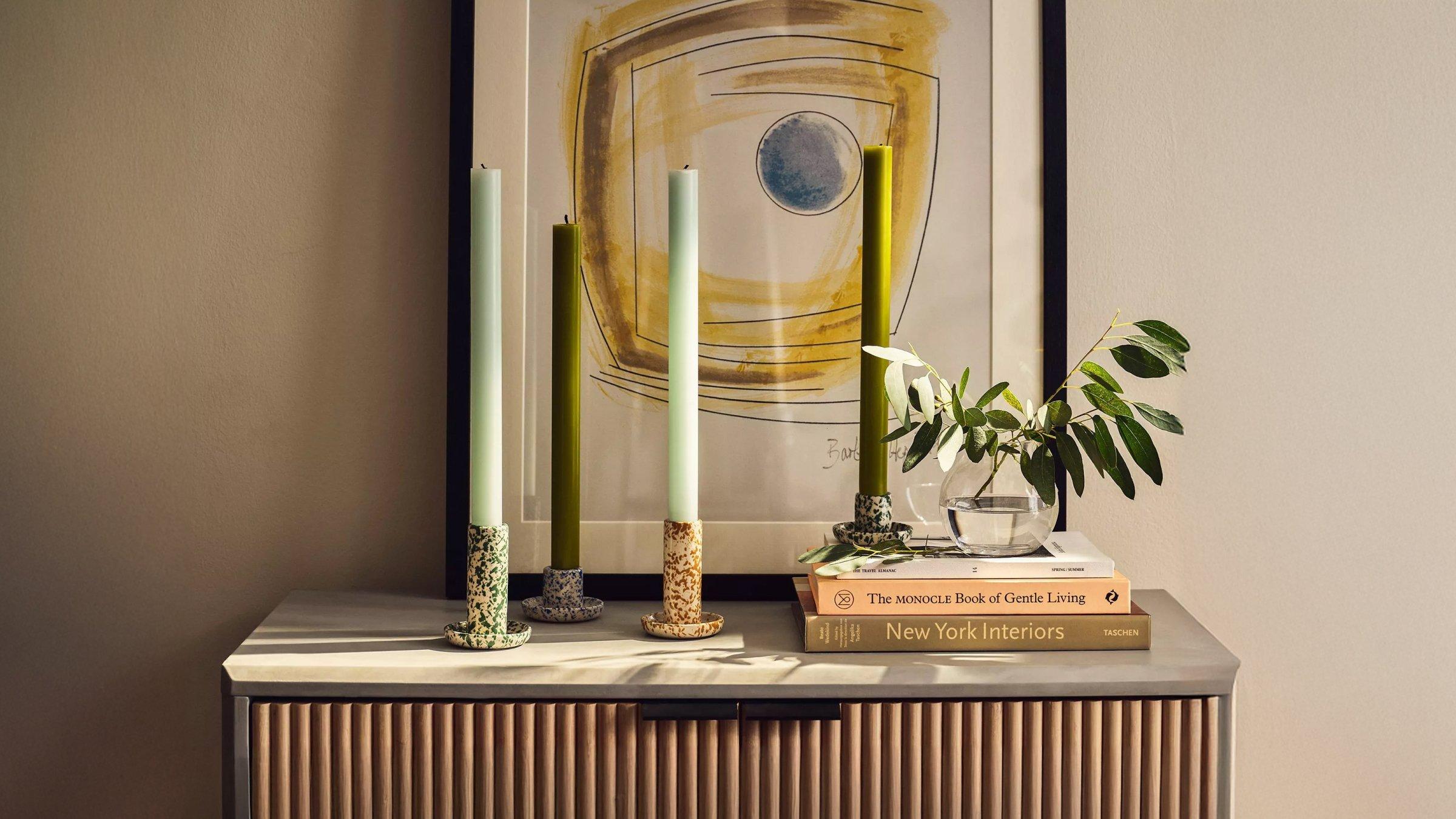 Selection of books and candle holders with candles displayed on top of the wooden side table
