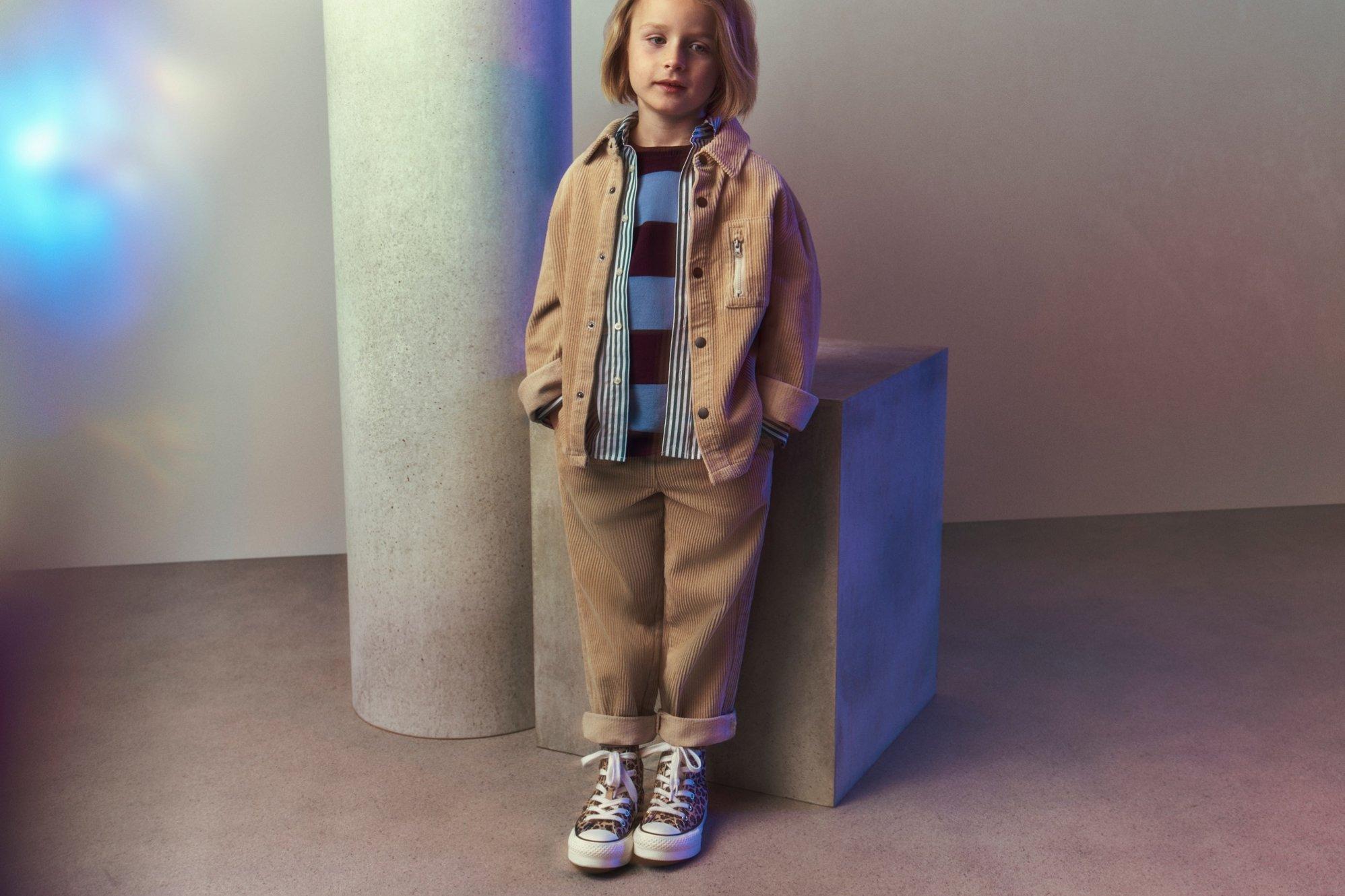 Boy standing wearing a beige co-ord and Converse trainers