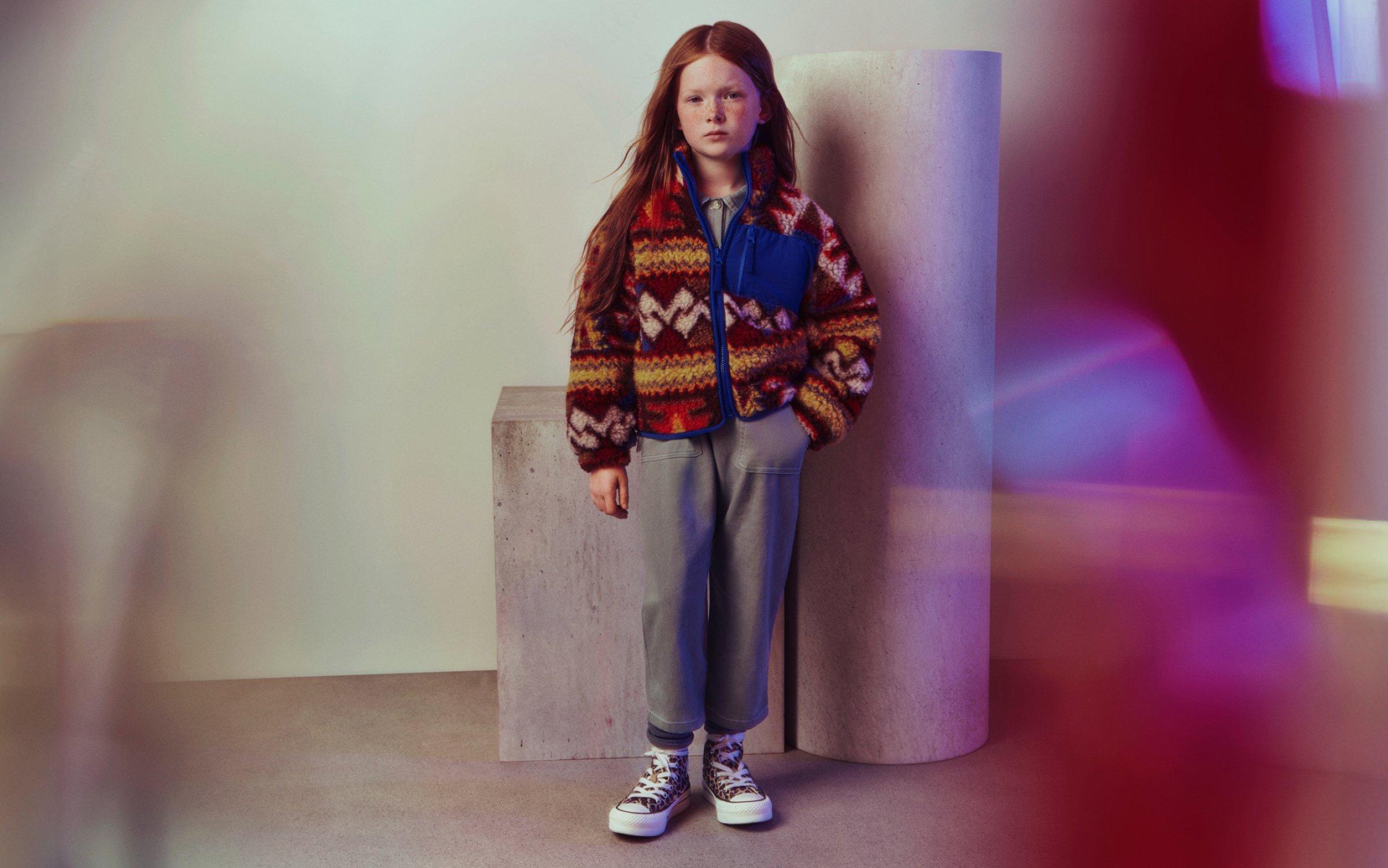 Girl standing wearing an autumn outfit and Converse trainers