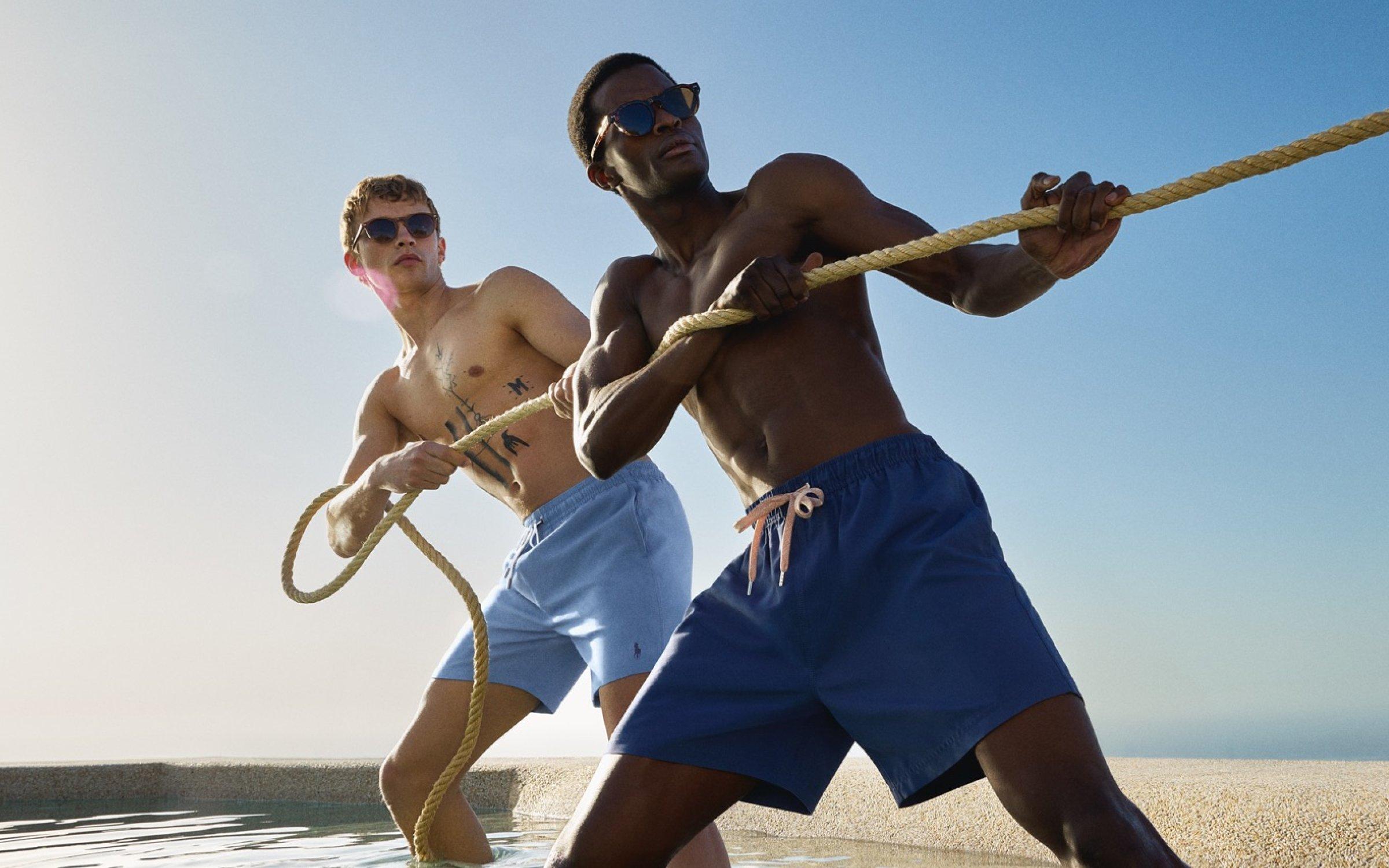 Two male models standing with their feet in water, playing tug of war