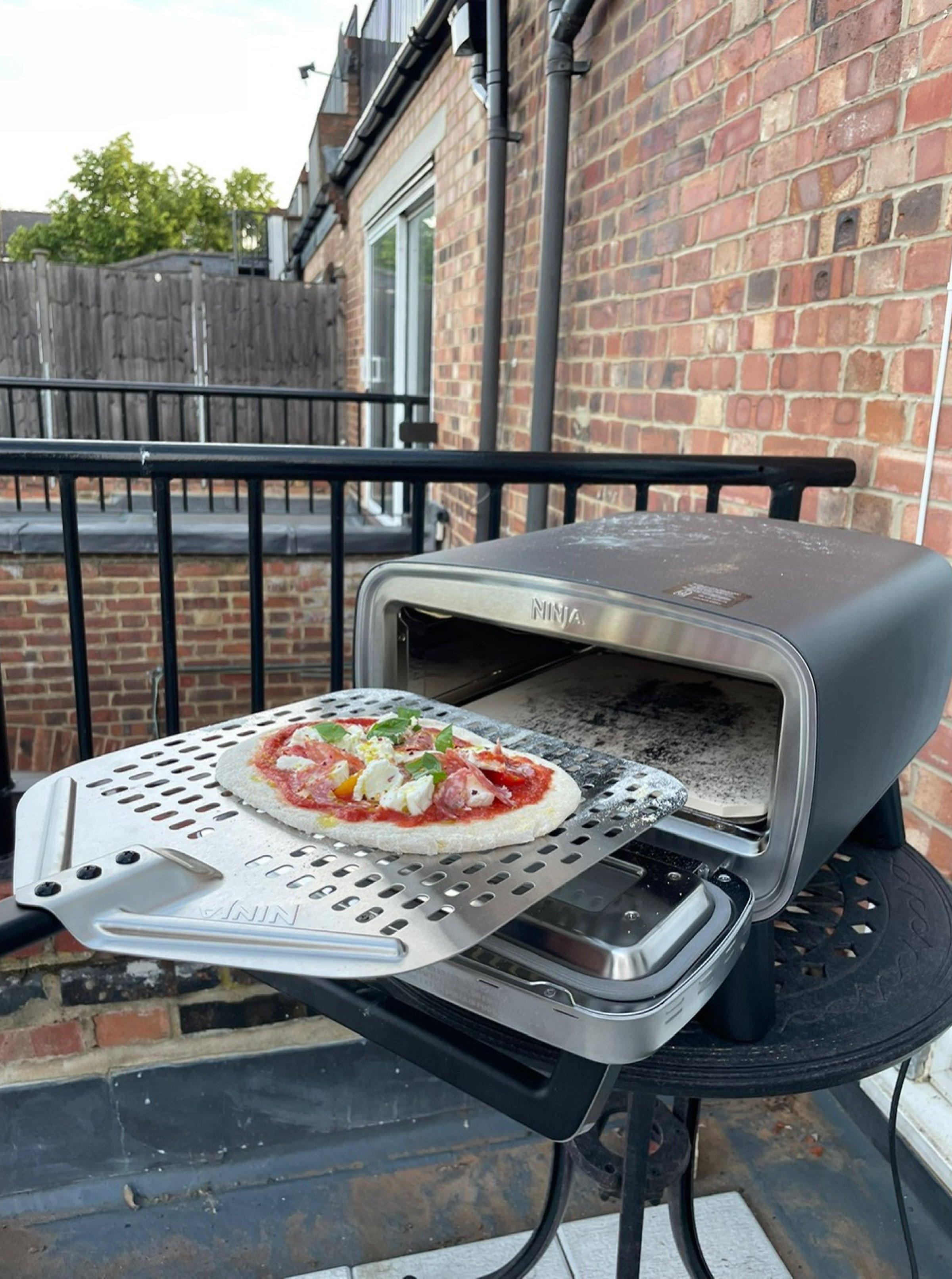 Ninja Artisan Electric Outdoor Pizza & Air Fry Oven with a pizza displayed outside