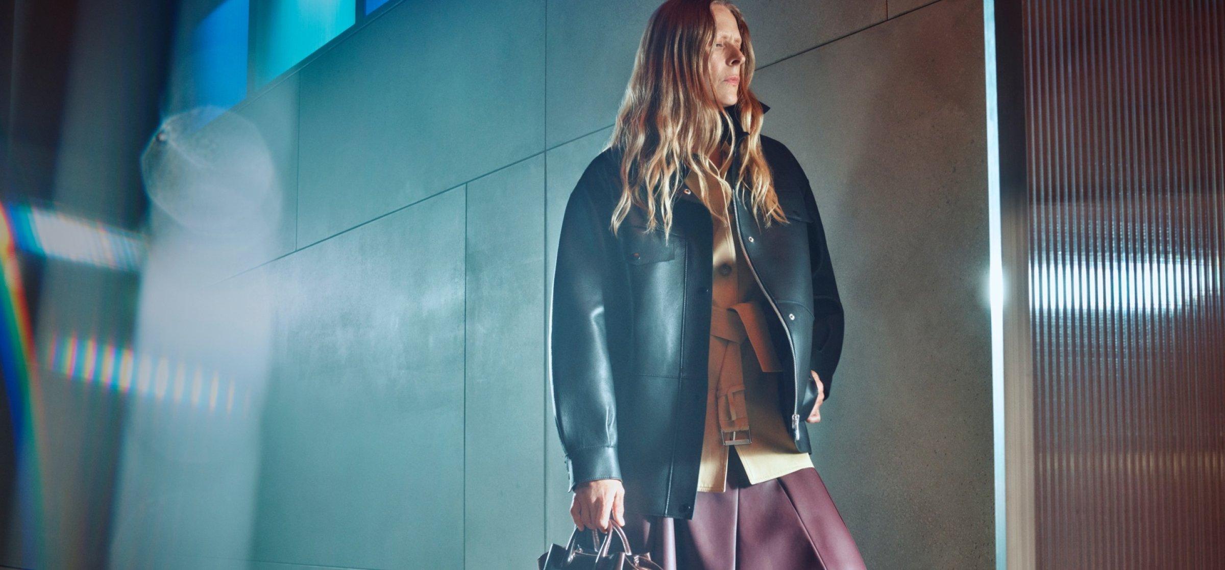 A female model in an autumn look with a black leather jacket, pausing