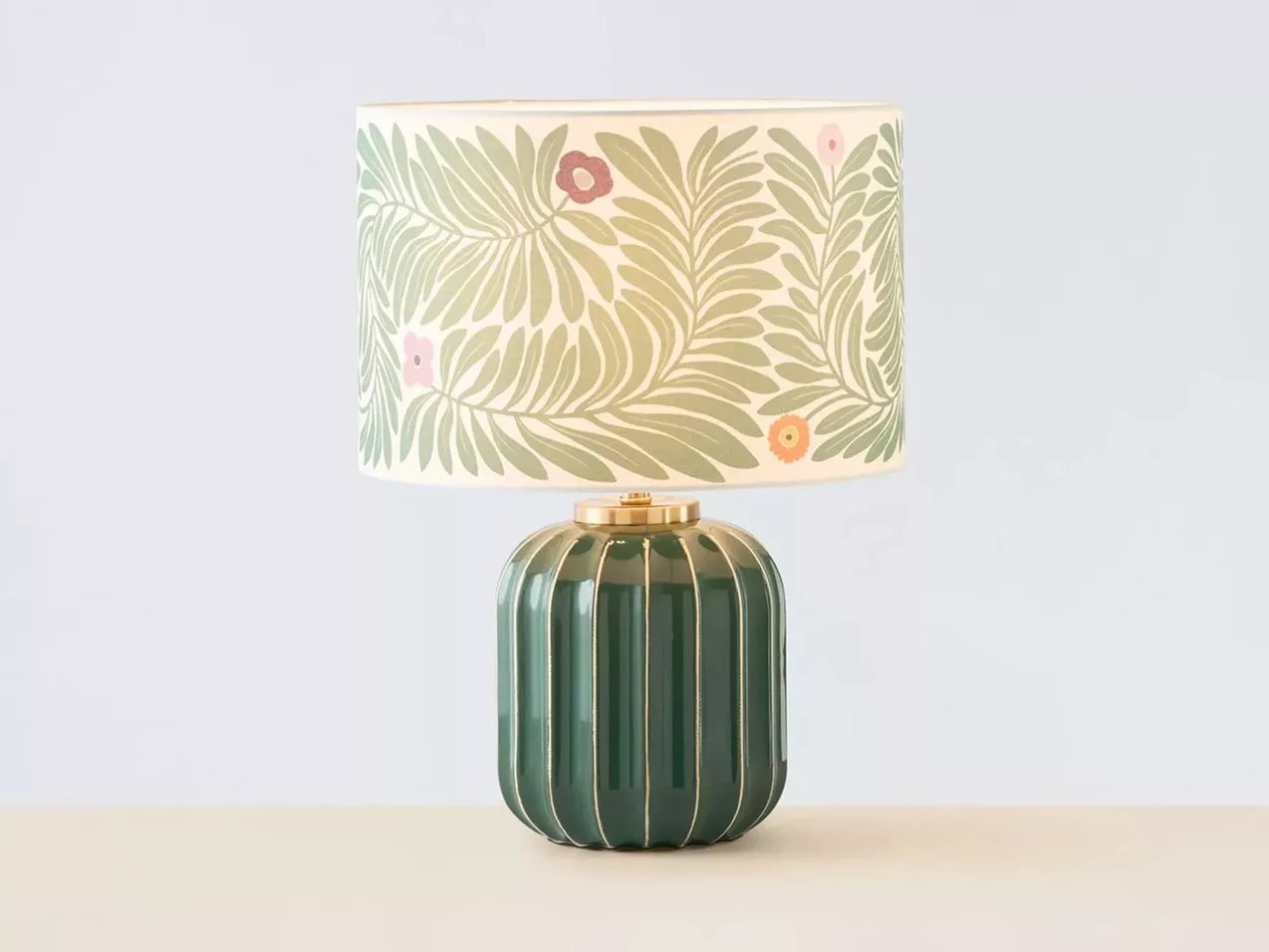 A green table lamp with a ribbed base and floral-patterned lampshade.