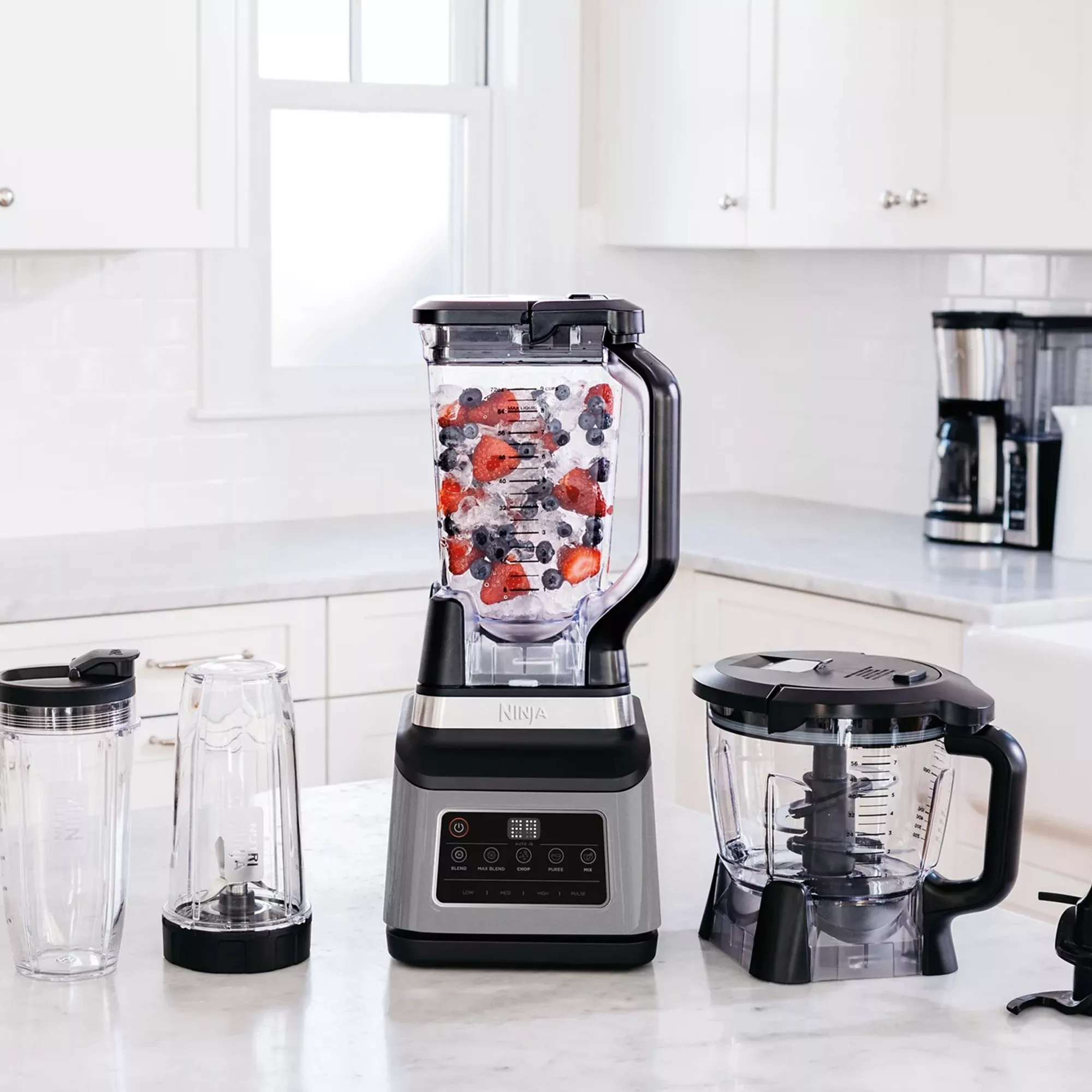 Blender with berry smoothie ingredients and multiple attachments