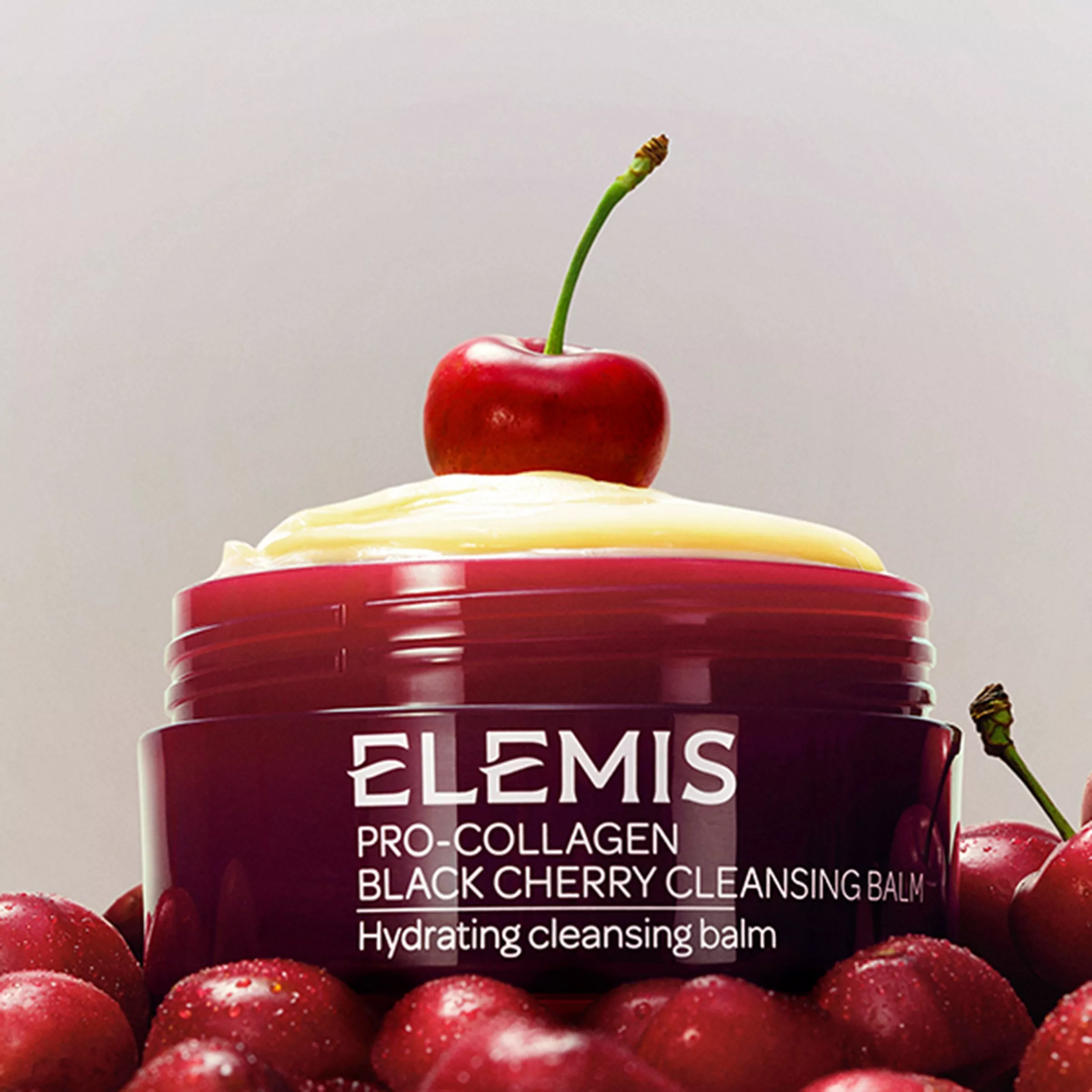 Open jar of Elemis cleansing balm surrounded by cherries