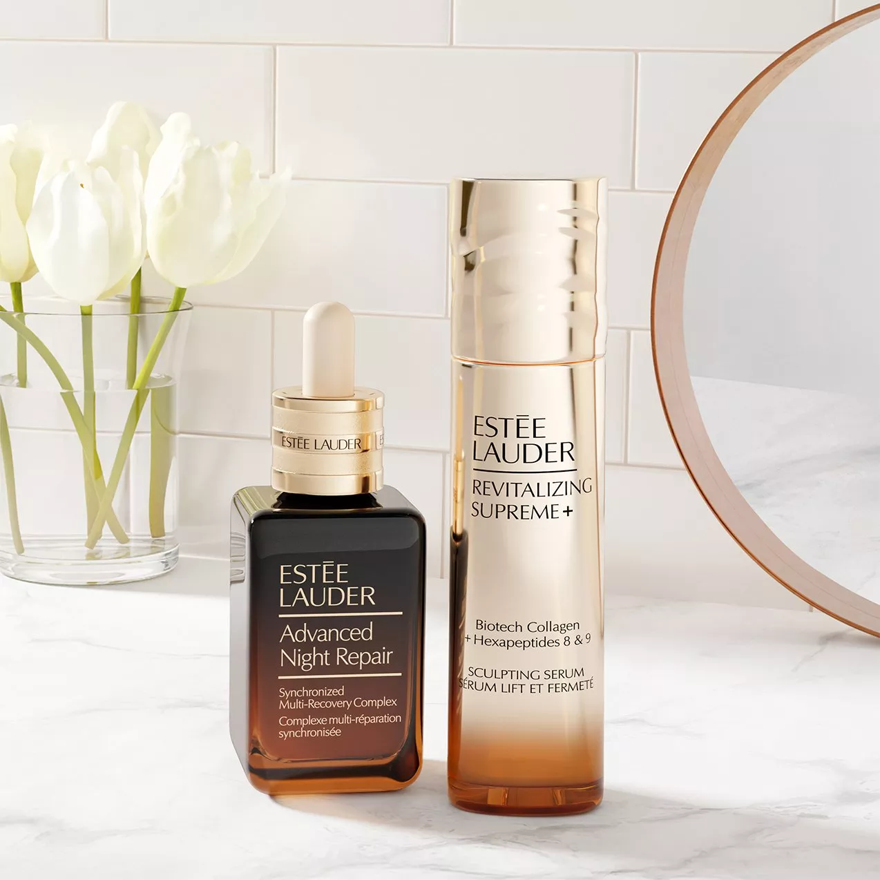 Estée Lauder Advanced Night Repair and Revitalizing Supreme+ sculpting serum on marble vanity with tulips