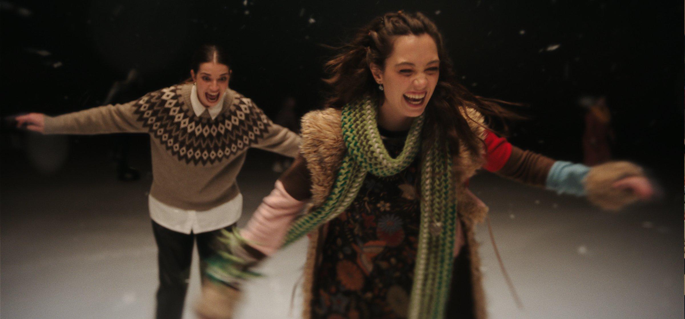 Two ladies Ice Skating wearing Christmas knitwear