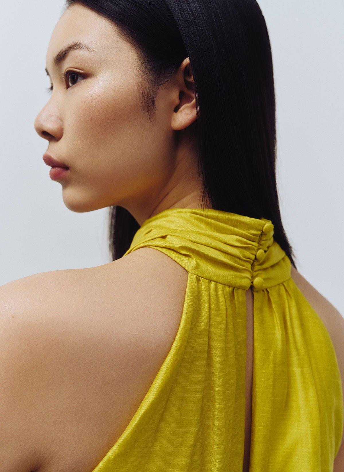 Close up of model wearing chartreuse halterneck linen dress