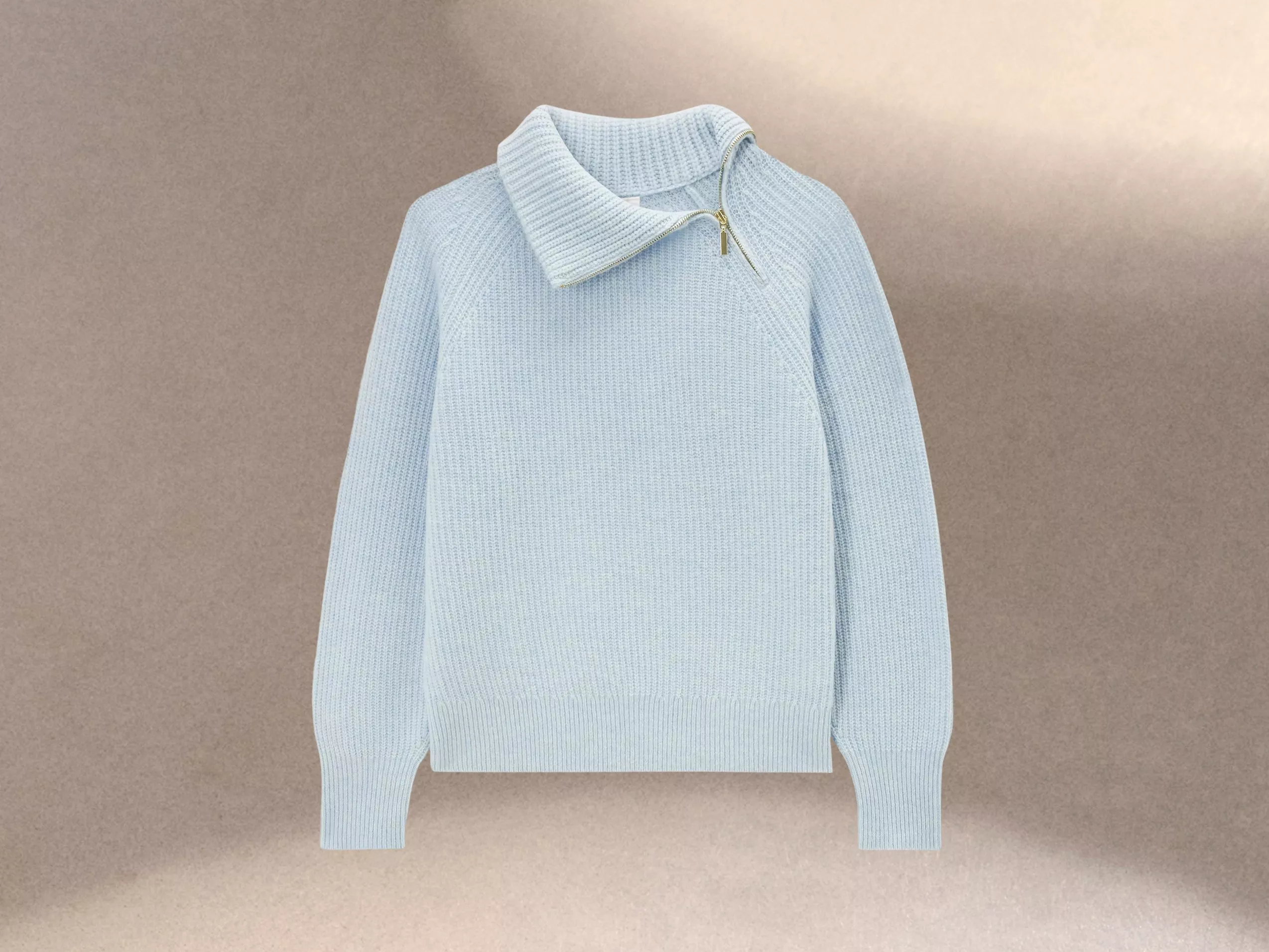 Light blue knitted jumper with a high collar and zip detail, set against a neutral background for stylish contrast.