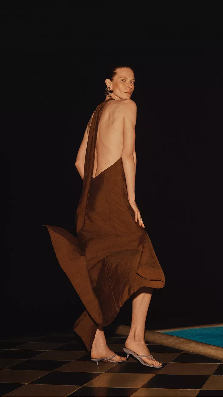 Models in elegant evening summer dresses, one backless satin brown dress and one orange satin dress