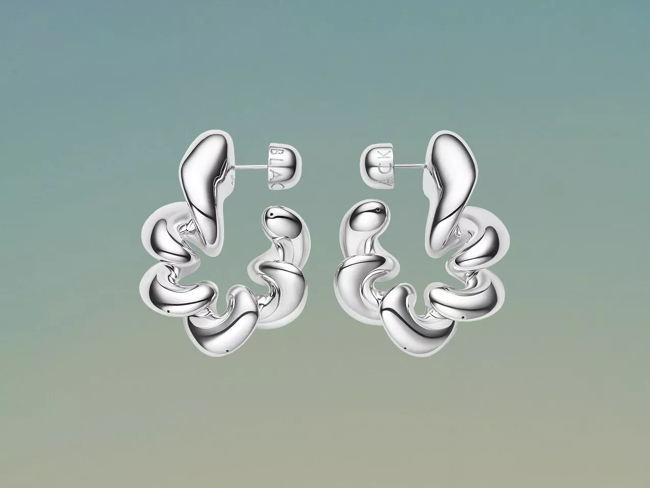 Polished silver sculptural hoop earrings with stud posts, modern statement jewellery on a soft green background