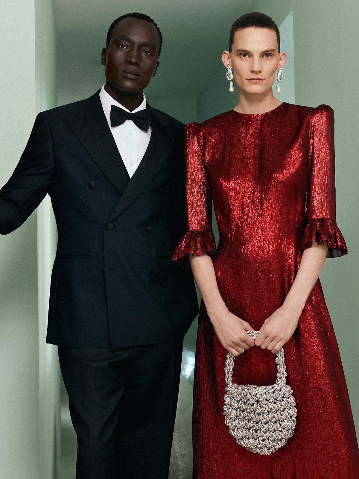 Man in tuxedo and lady in red sparkly dress holding handbag