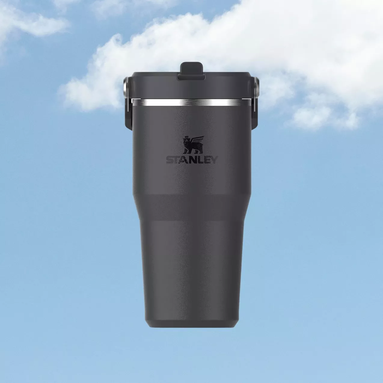Black Stanley insulated travel tumbler with flip lid, stainless steel band, on blue sky background with clouds