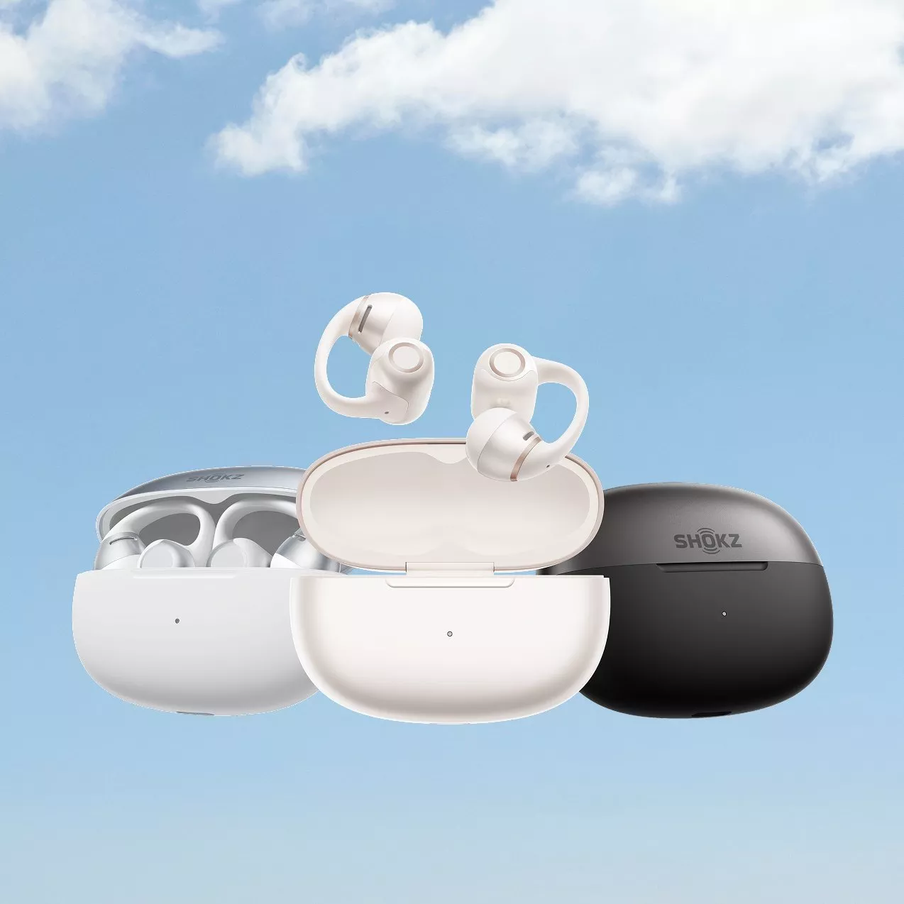 Shokz wireless earbuds with charging cases in white, beige and black, floating against blue sky background